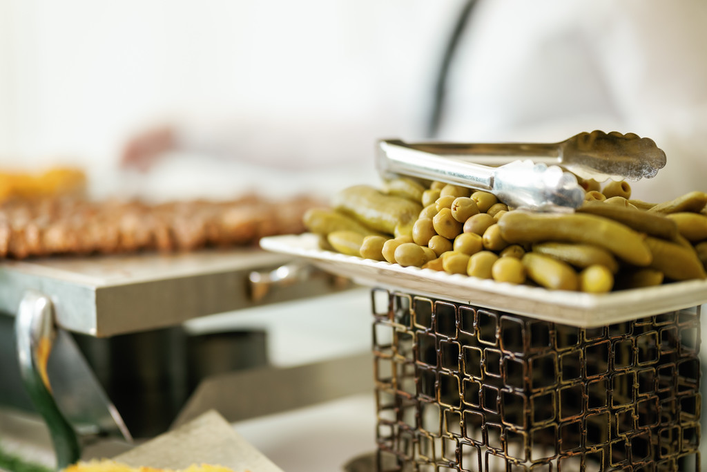 Close-up of olives and produce in a serving tray during a Jewish wedding celebration, with a softly blurred background.