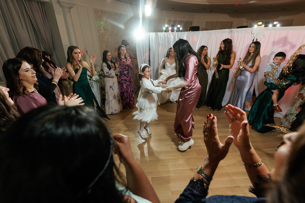 Guests clap and cheer on the dance floor as the bride and groom dance at a Jewish wedding/mitzvah celebration.