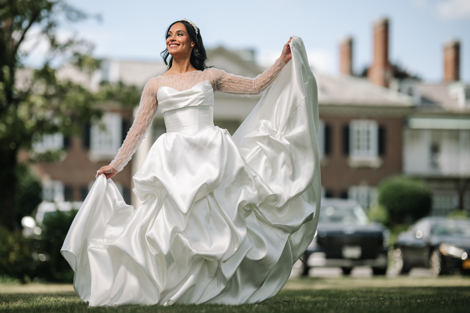 Woman in a white wedding gown smiling while lifting her veil during at The Mansion At Glen Cove, photographed by CJ Studios