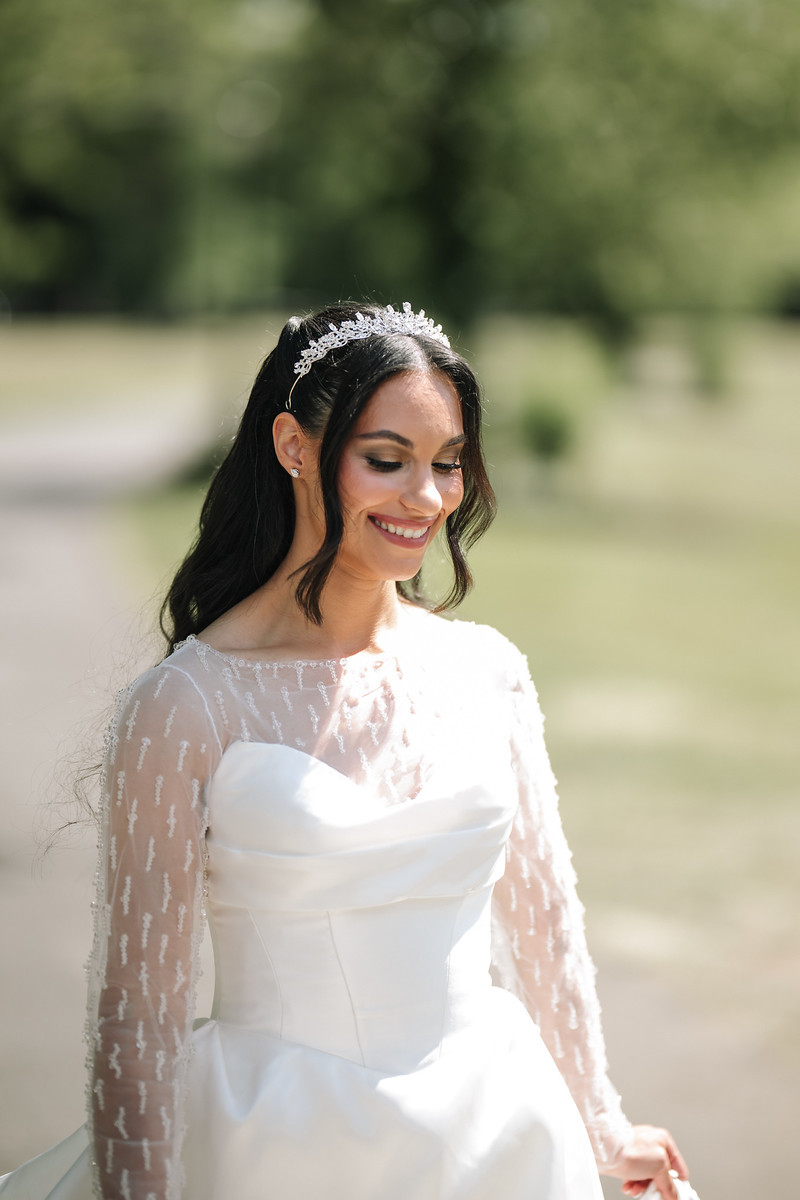 Bride in a white lace veil and tiara smiling outdoors in soft at The Mansion At Glen Cove, photographed by CJ Studios