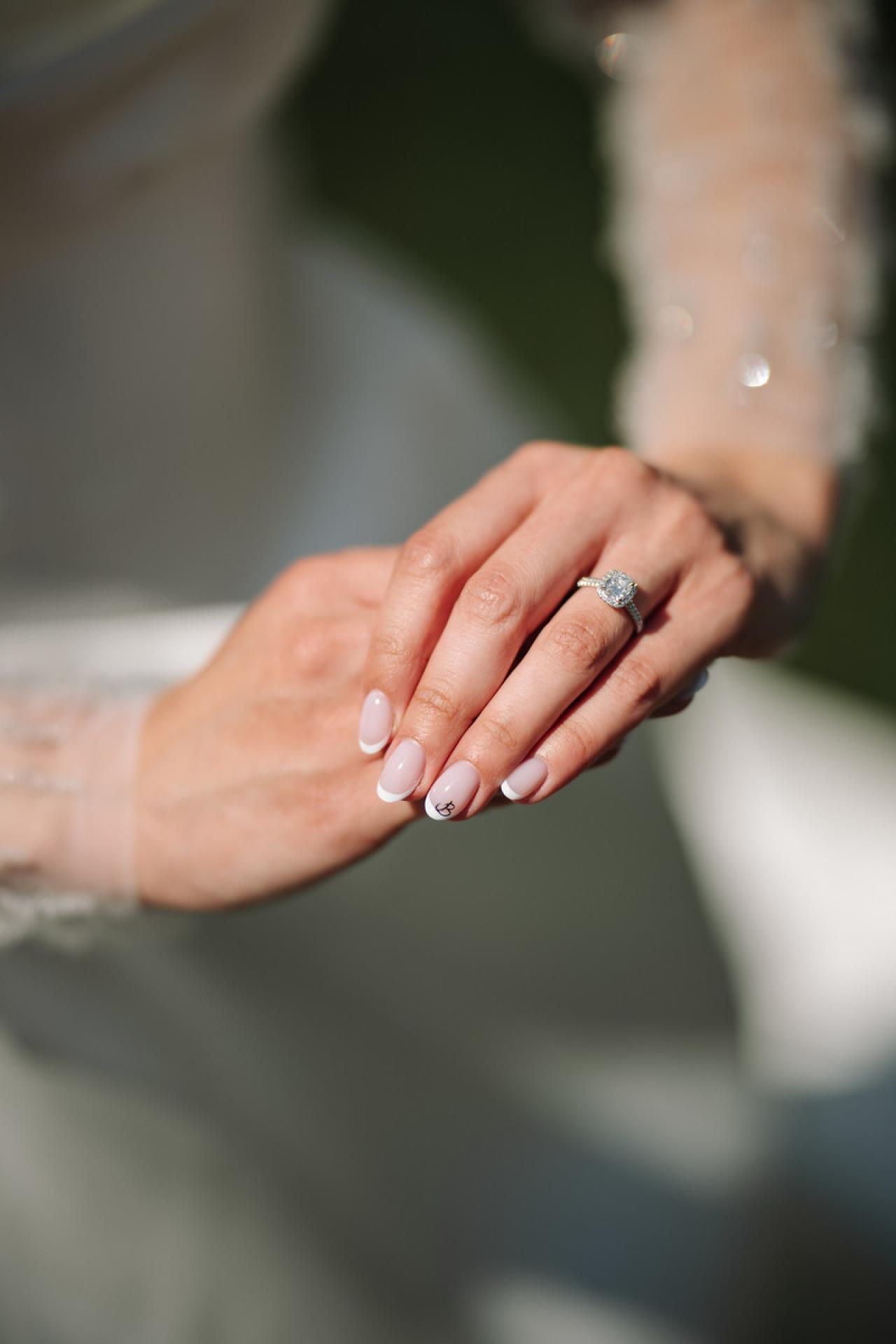 Close-up of two hands clasped together, showing an engagement ring at The Mansion At Glen Cove, photographed by CJ Studios. Wedding photography.