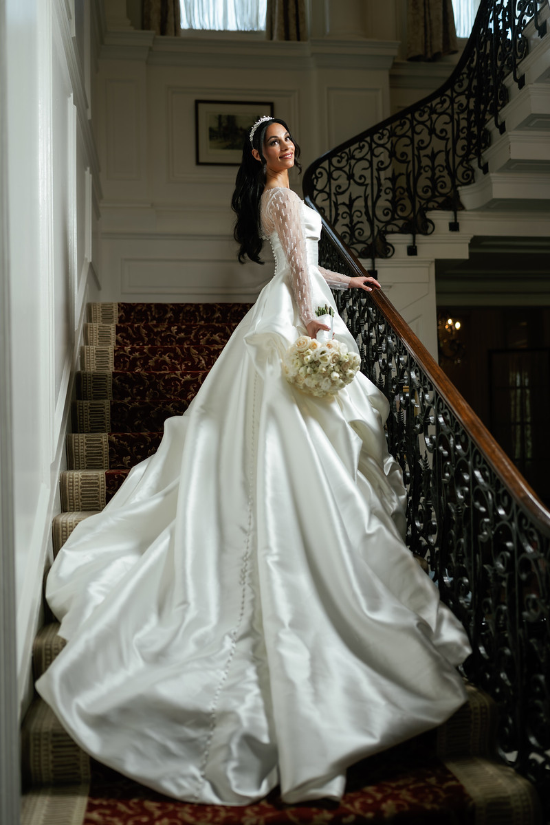 Frum bride in a white gown and headpiece standing on a staircase at The Mansion At Glen Cove, photographed by CJ Studios
