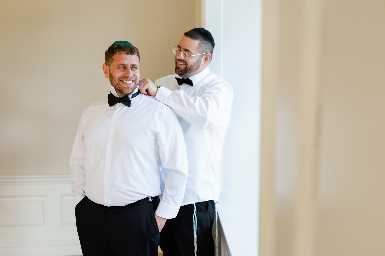 Two men in black yarmulkes and white shirts share a warm smile; one at The Mansion At Glen Cove, photographed by CJ Studios