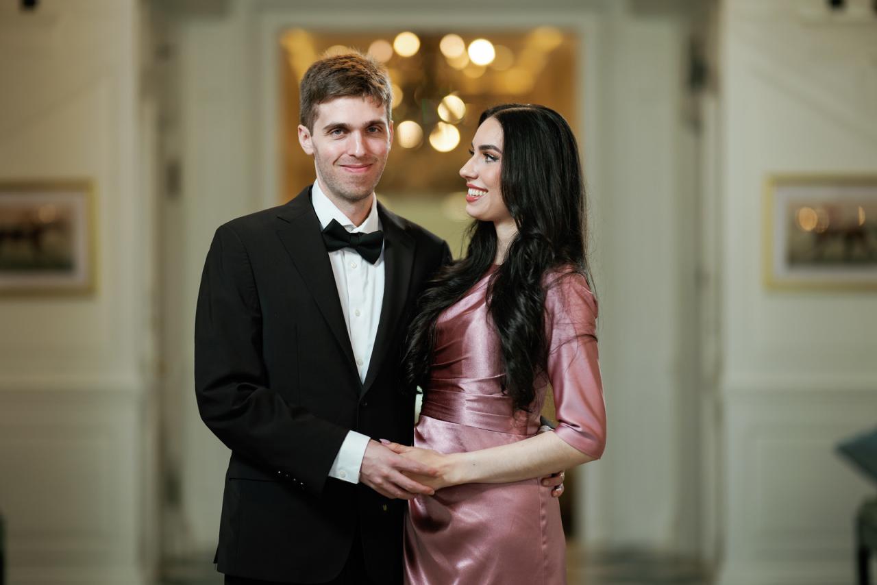 Smiling groom and bride standing together in formal attire, holding at The Mansion At Glen Cove, photographed by CJ Studios. Wedding photography.