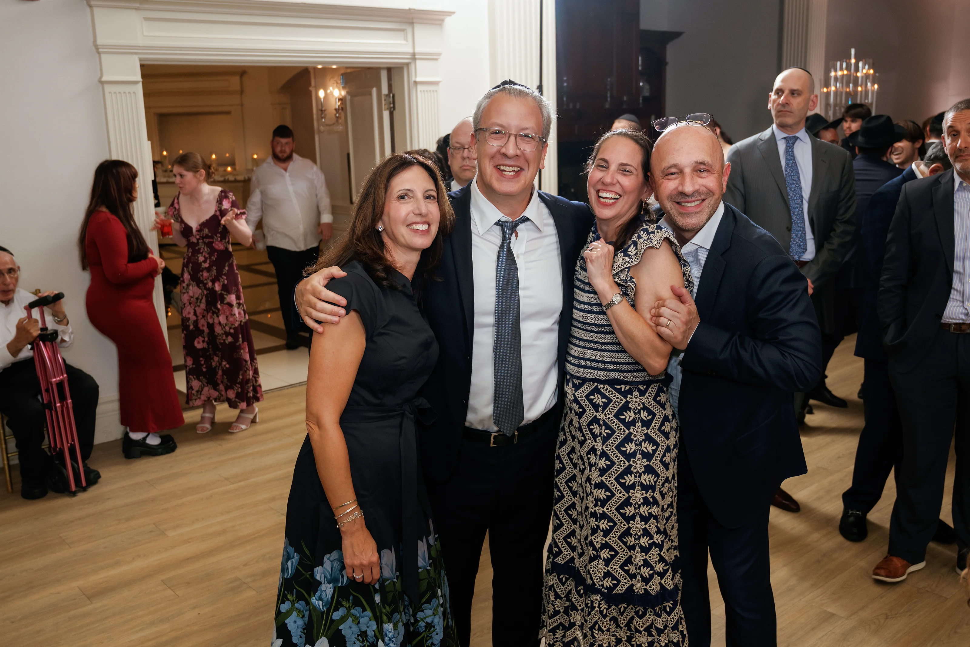 Close family group laughing together during a wedding dance in a ballroom, arms around each other and joyful faces.