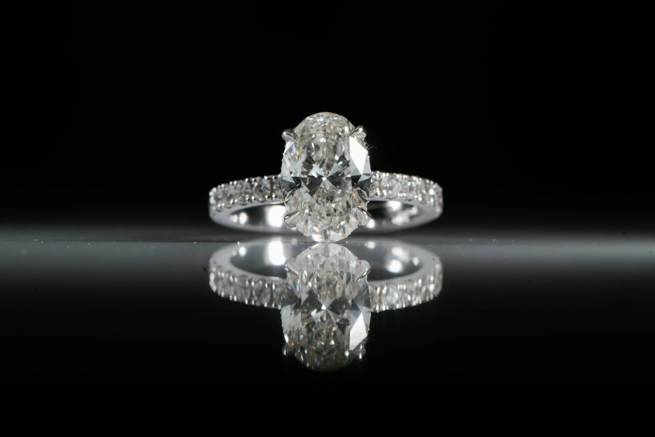 Macro studio photo of a diamond engagement ring centered on a reflective surface with a black background. Wedding photography at Sands, Atlantic Beach, NY.