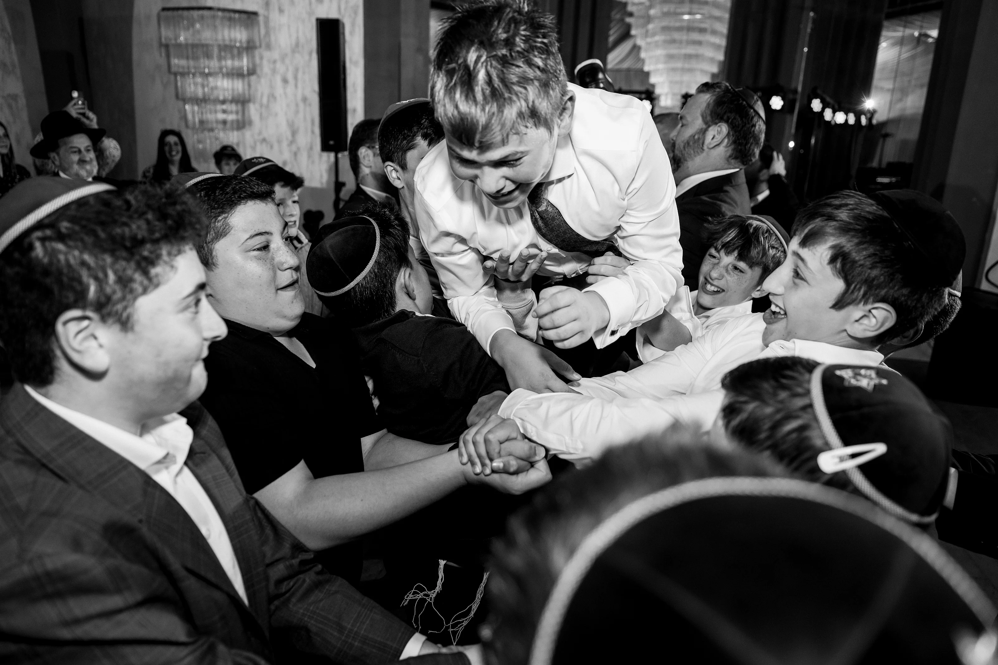 Black-and-white reception photo of a man holding a laughing toddler at center while family and guests smile around them.