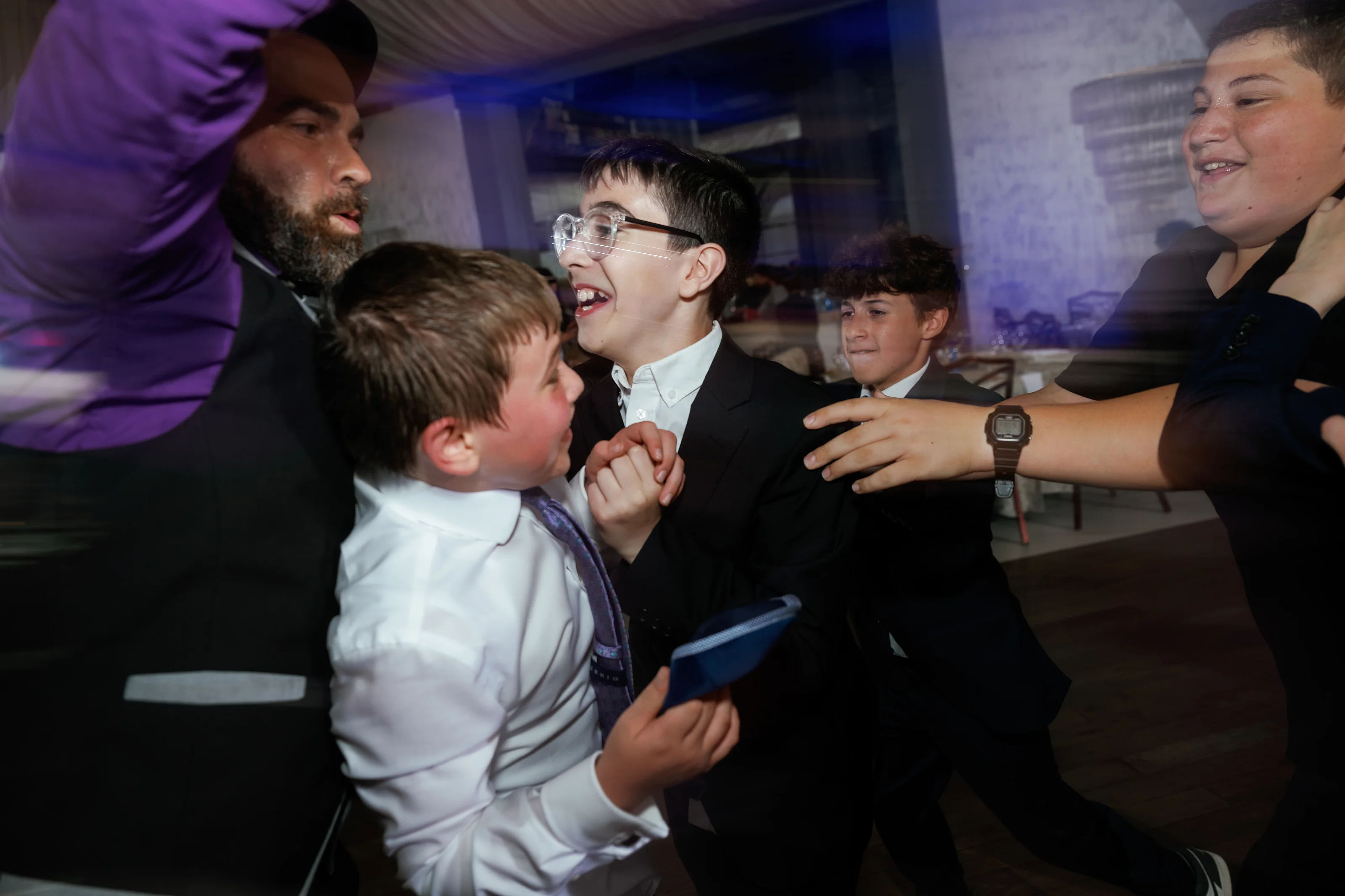 Dance-floor celebration with multiple joyful faces clustered together under purple and blue lighting.
