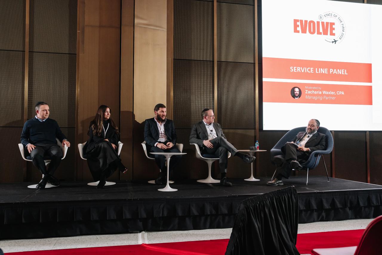 Seated panelists on a stage in front of a large screen reading “SERVICE LINE PANEL,” photographed during a conference panel discussion.