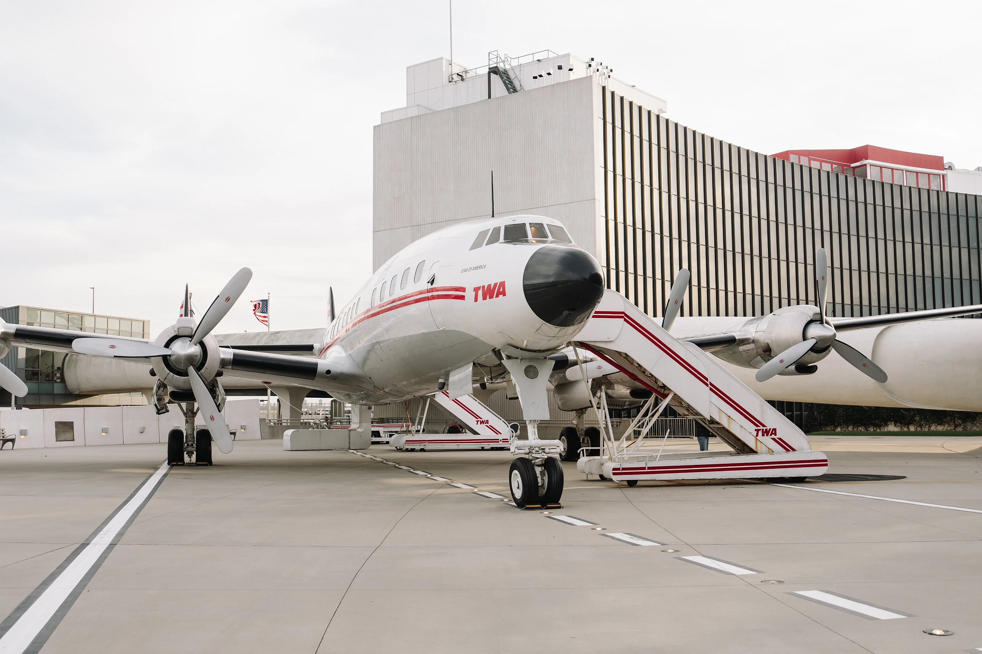 Wide view of a passenger airplane parked at an airport gate beside a terminal building.
