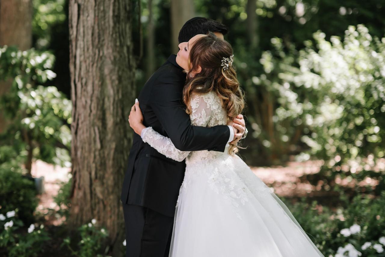 Bride and groom embracing closely outdoors, foreheads touching, with greenery and trees softly blurred in the background. Wedding at Crystal Plaza, Livingston, NJ.