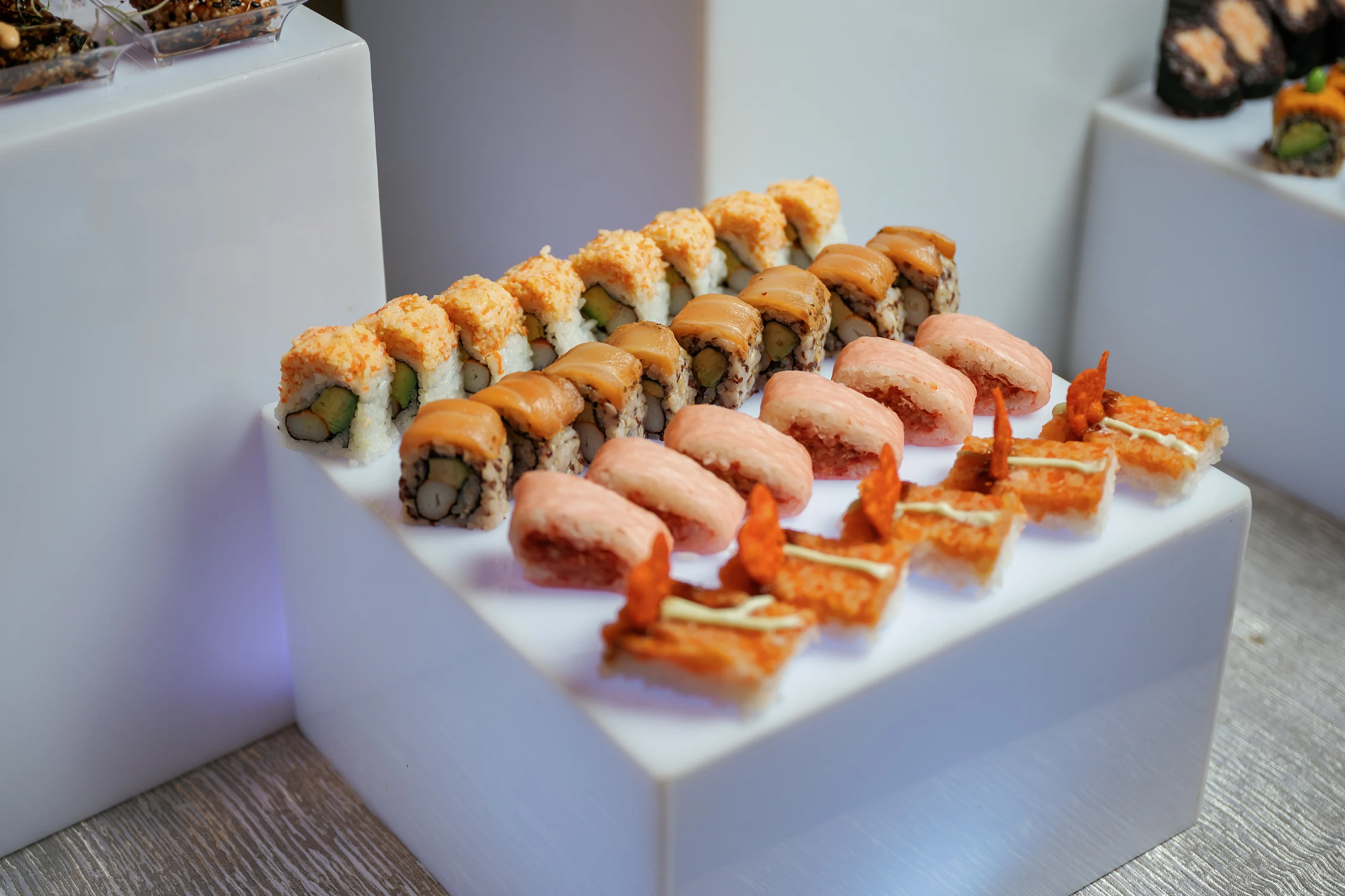 Sushi rolls and appetizers arranged on a white display