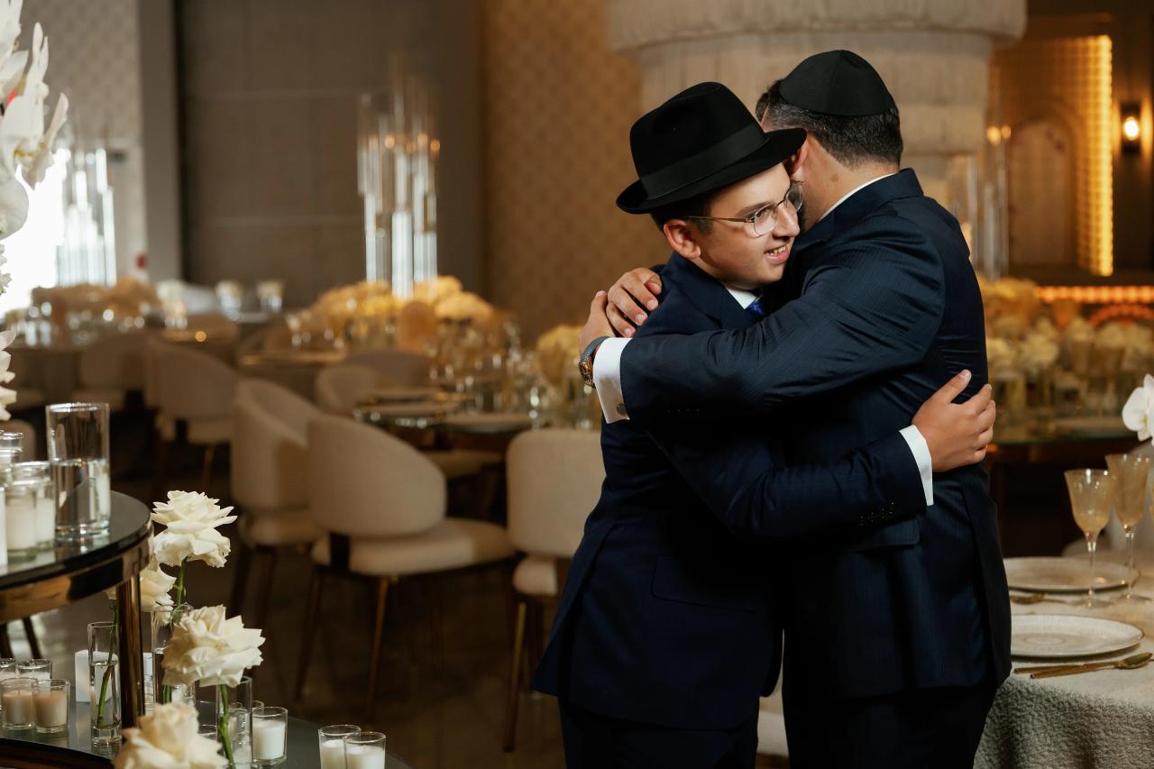 Two guests share an embrace during the Bar Mitzvah reception