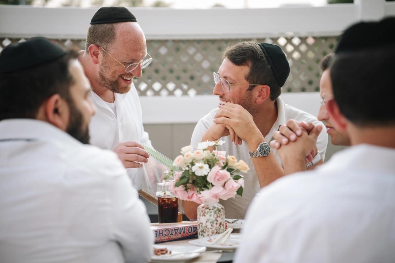 Guests share a laugh at a Bar Mitzvah table with a floral centerpiece