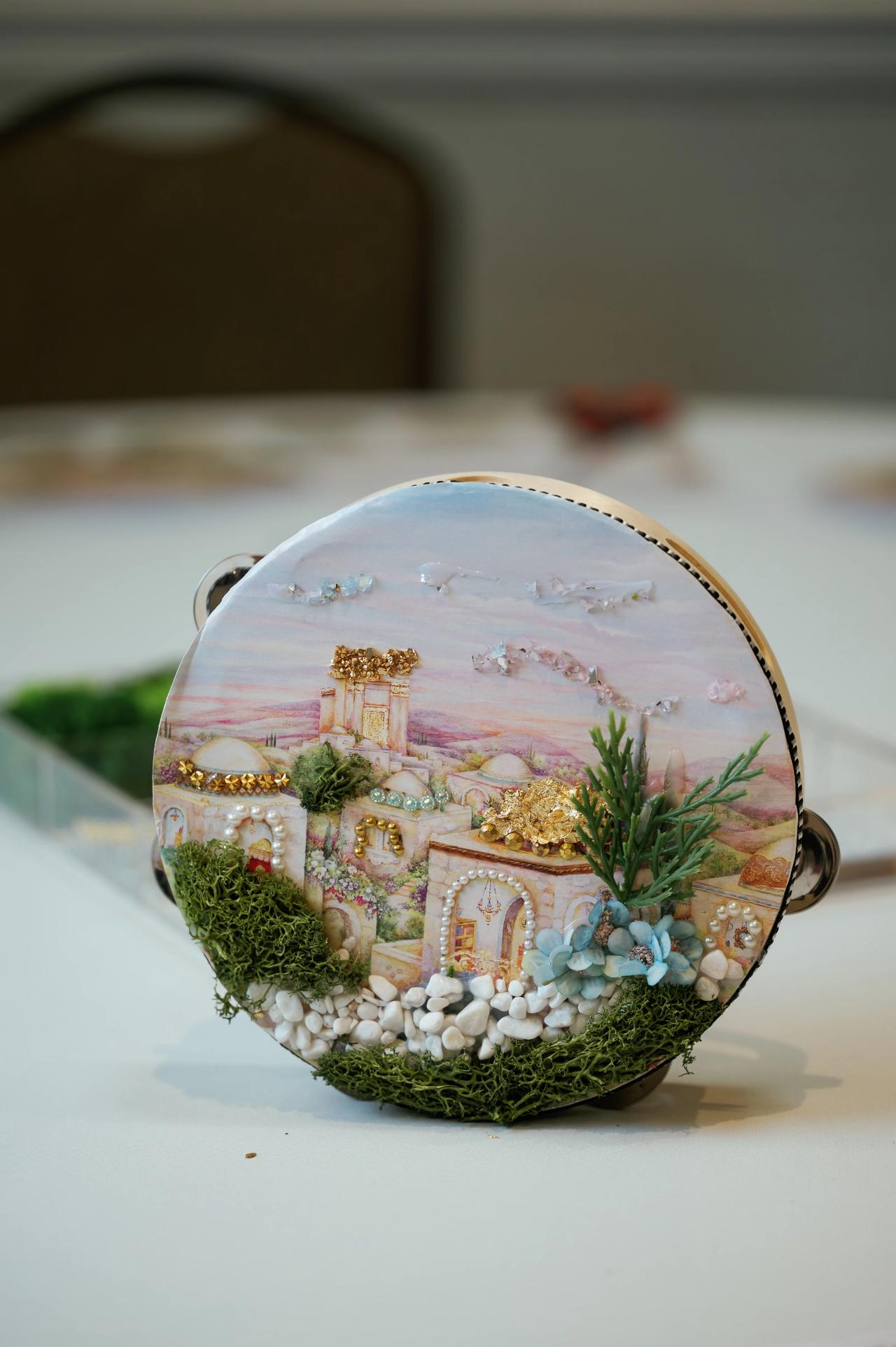 Painted tambourine decorated with greenery on a table