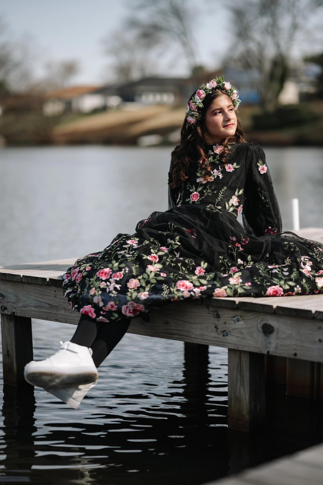 Girl seated on a wooden dock above the pond