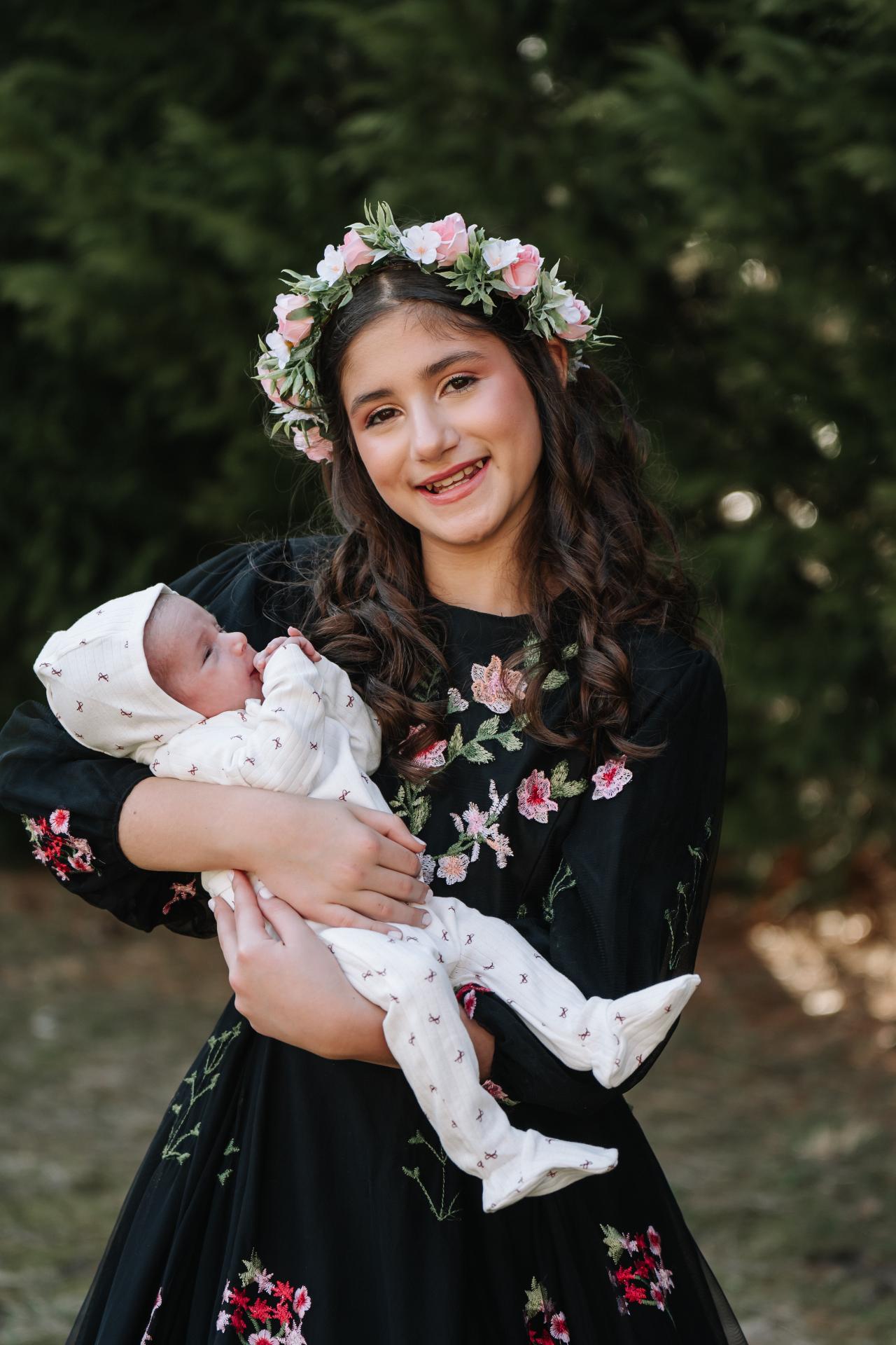 Girl holding a sleeping baby during outdoor family portraits
