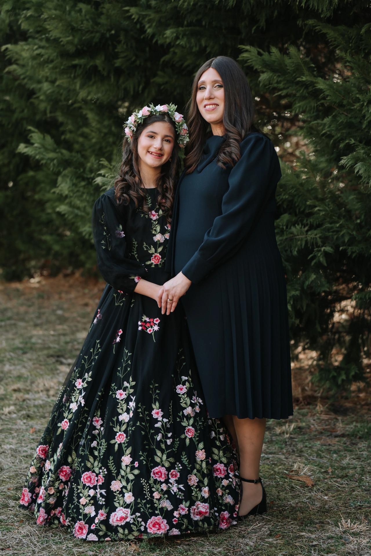 Girl and woman posing together beneath the trees