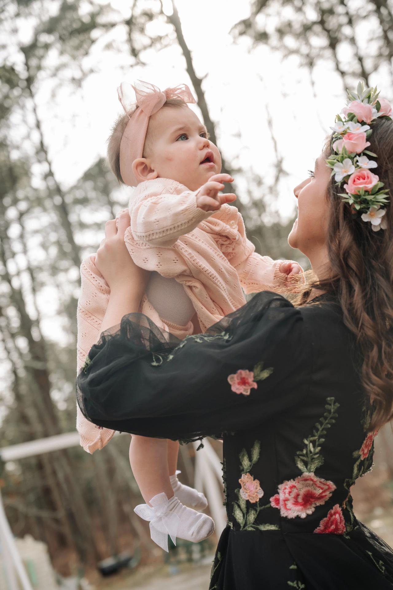 Girl lifting a baby during a playful outdoor family moment