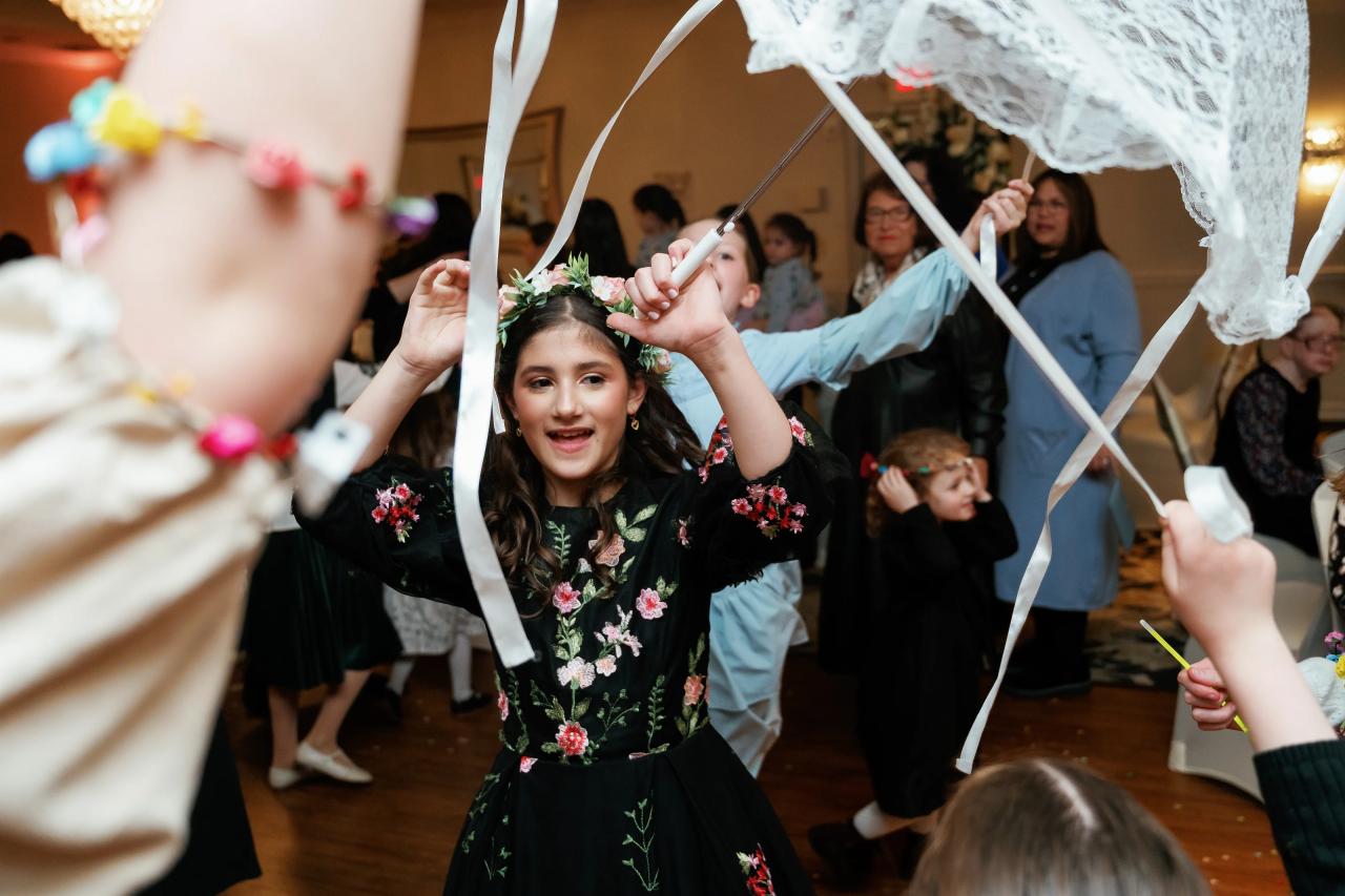 Bat Mitzvah girl smiling beneath raised ribbons