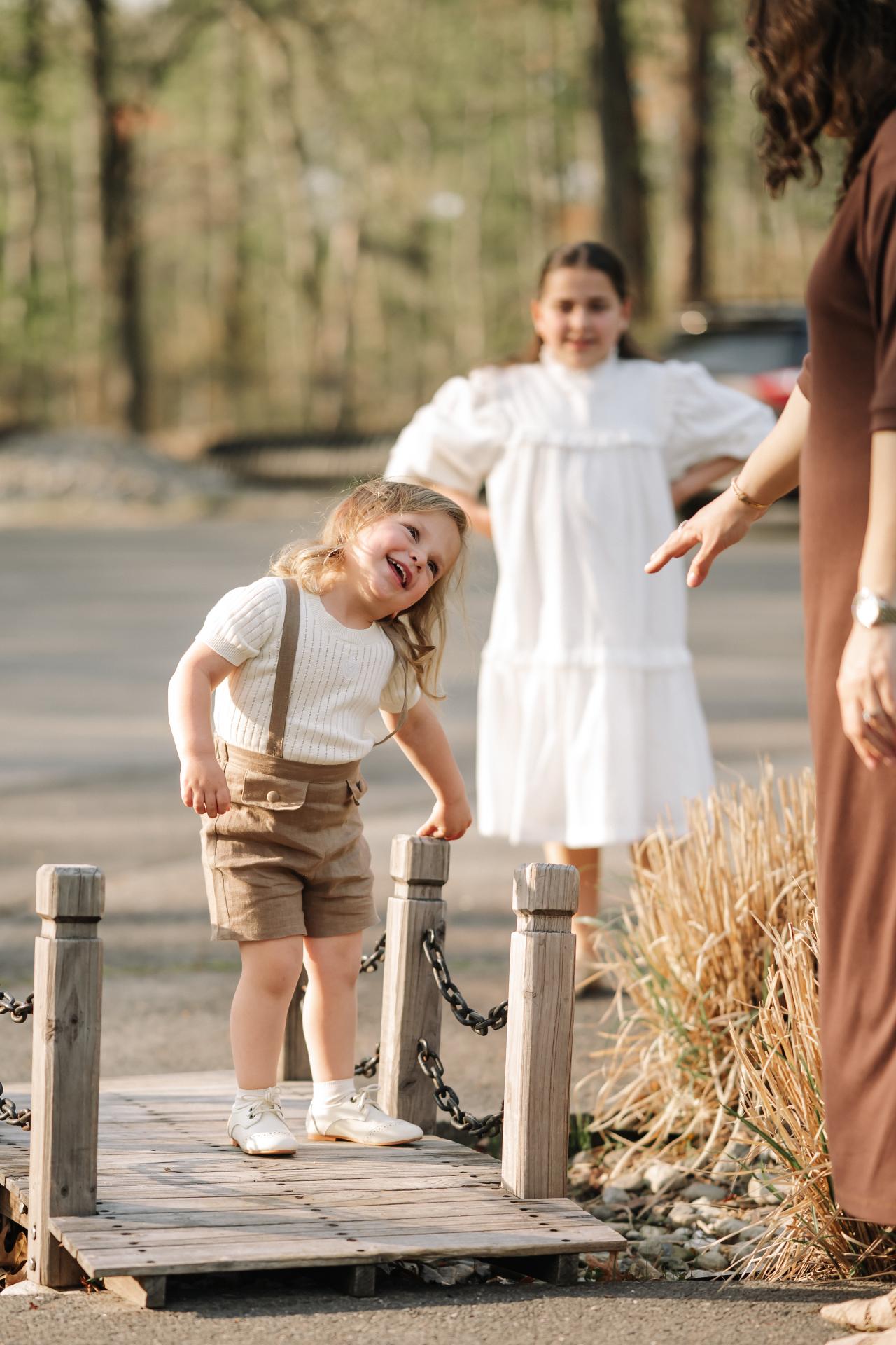 Young child tilting his head playfully on a small wooden bridge