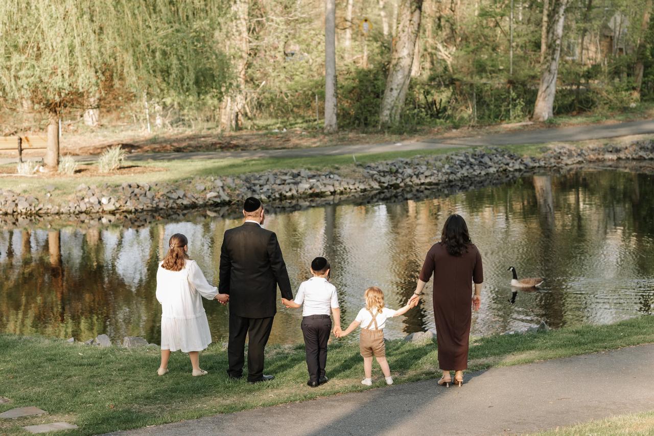 Family of five standing together at the edge of a pond