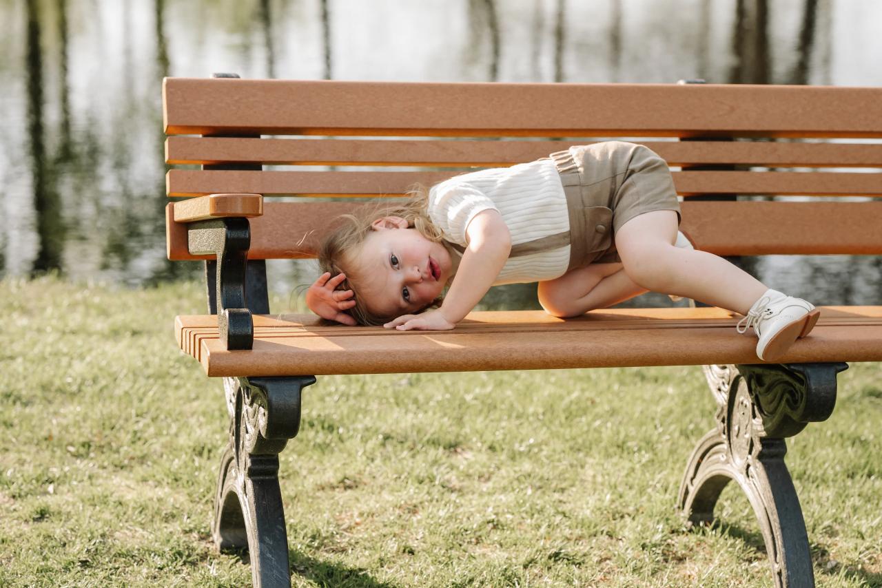 Child lying playfully across a wooden bench during Upsherin portraits