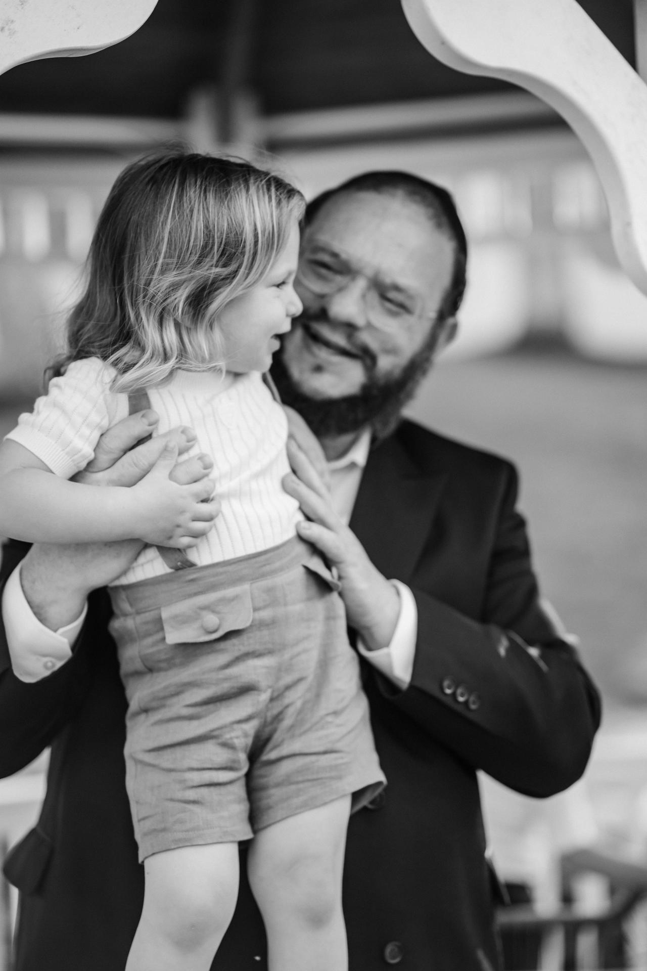 Black-and-white portrait of a father kissing his young child