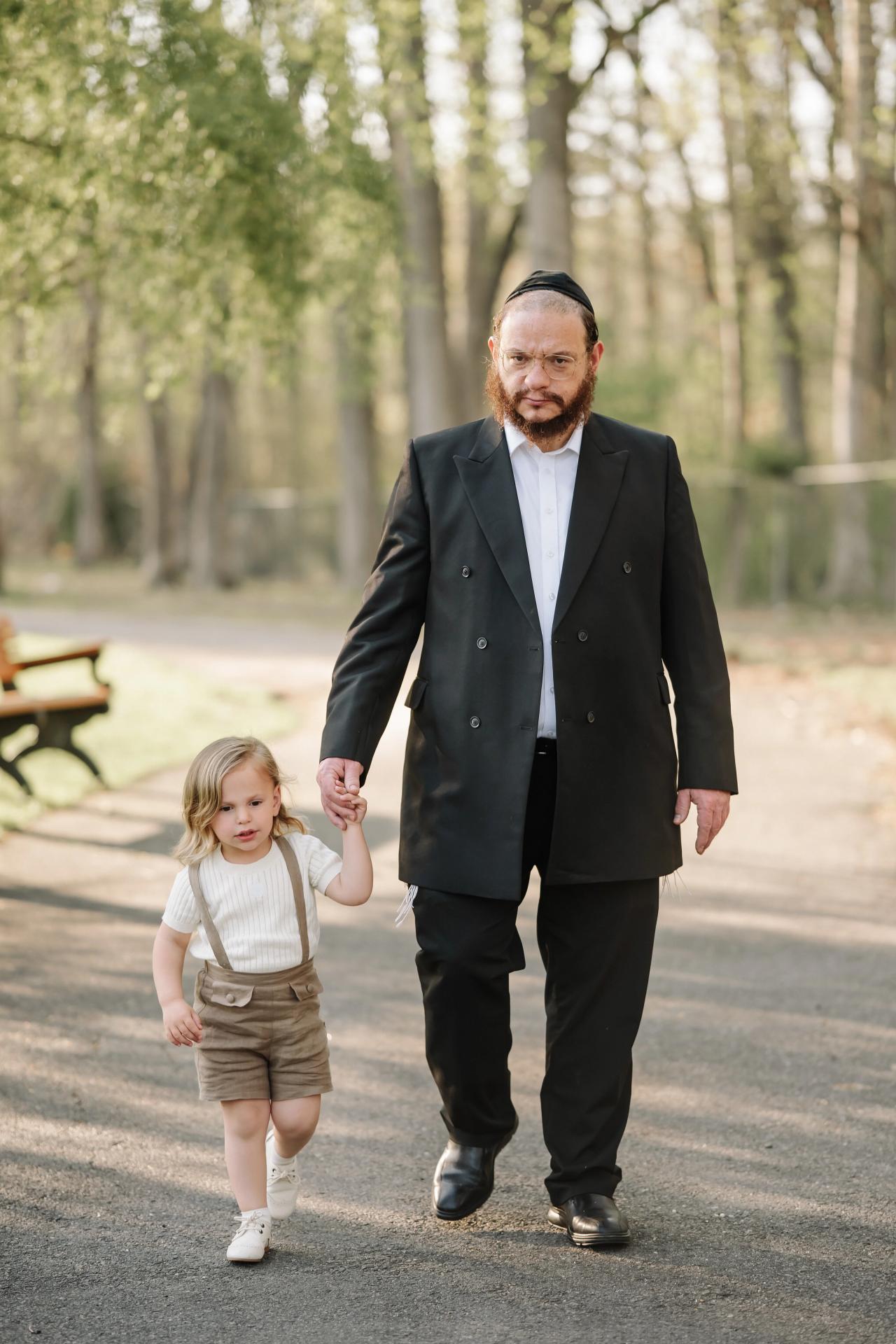 Father and child holding hands while walking through the park
