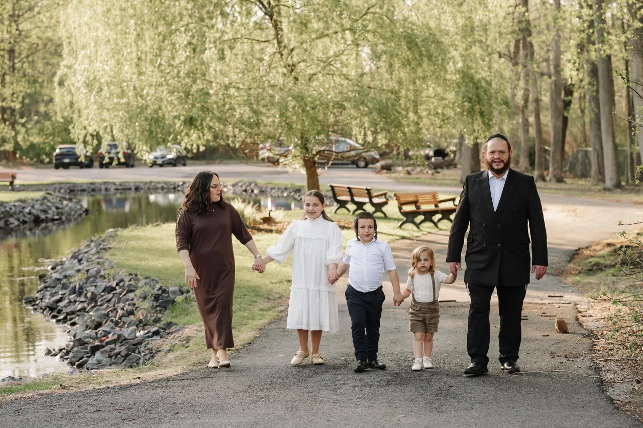 Family walking together along a tree-lined park path