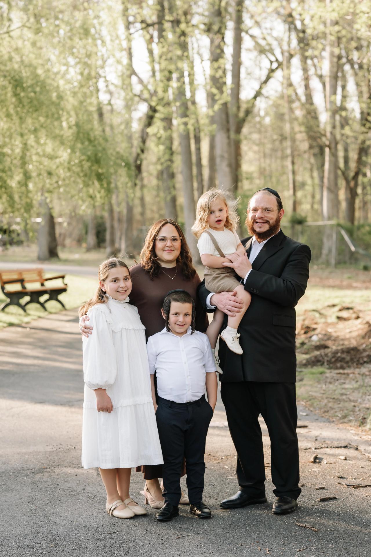 Close family portrait with parents and three children outdoors