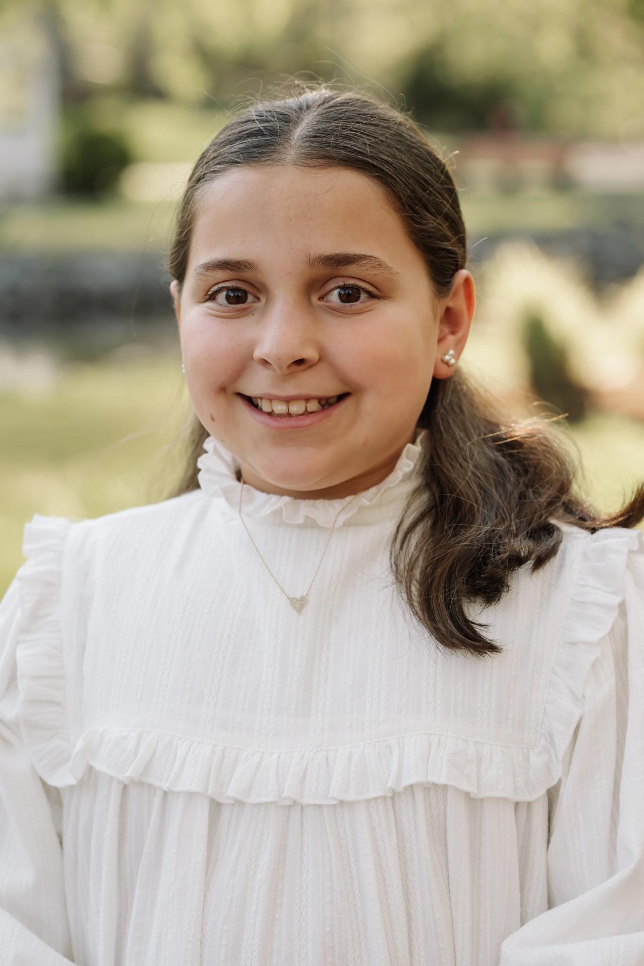Smiling girl in a white dress during an outdoor family portrait session