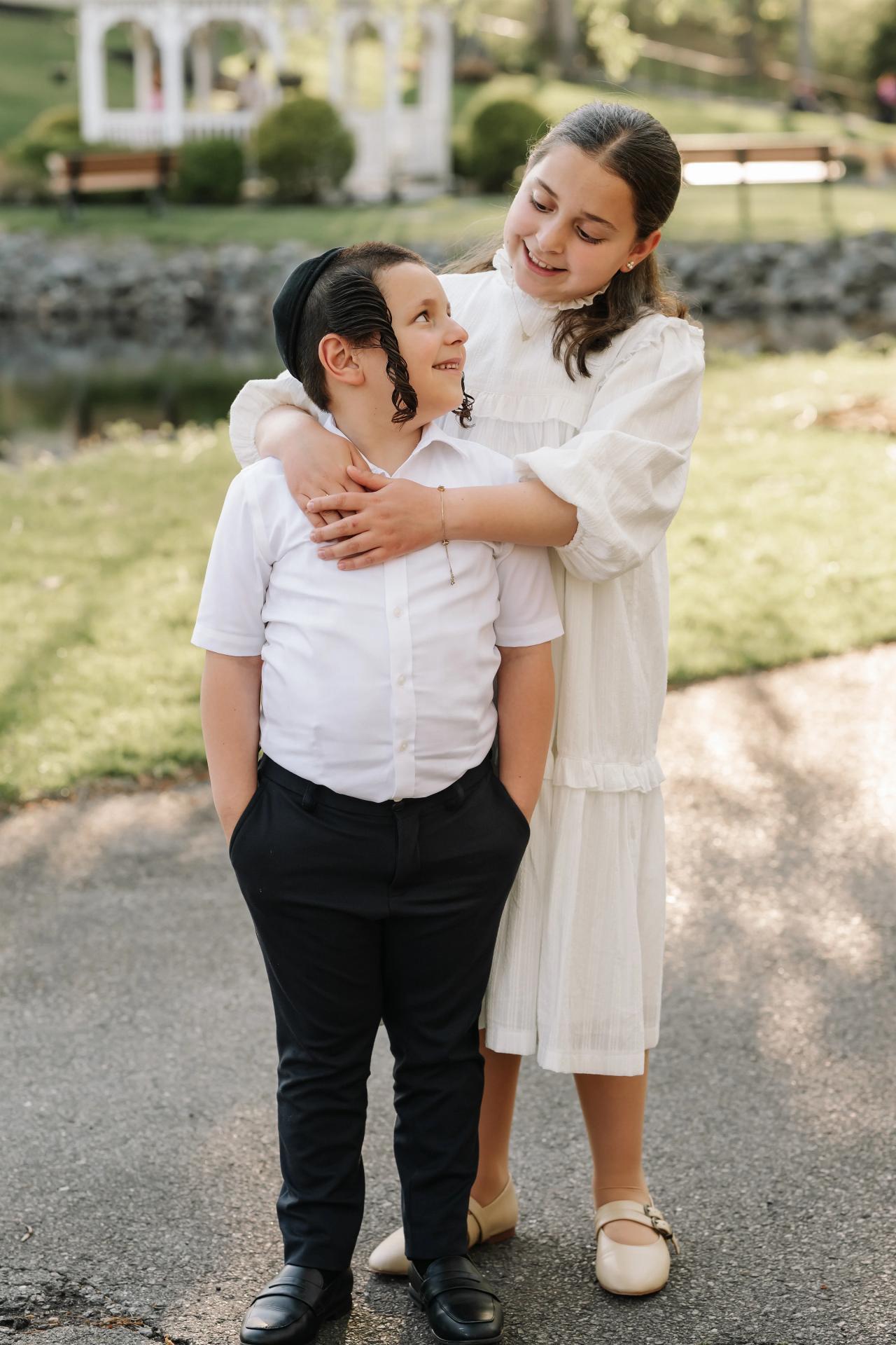 Sister and brother sharing a smile beside a pond