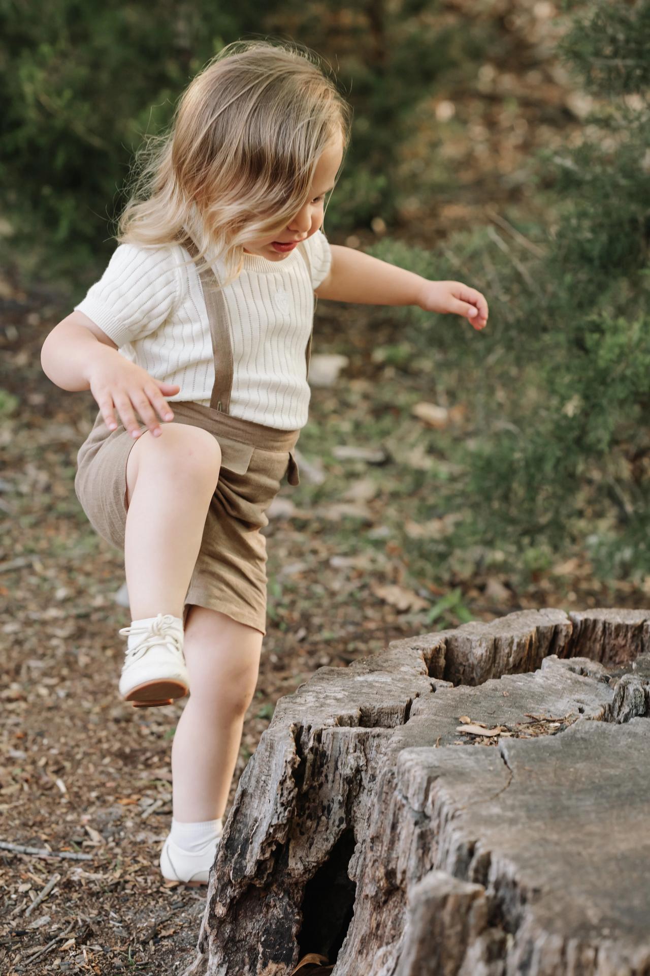 Young child stepping carefully down a low stone ledge