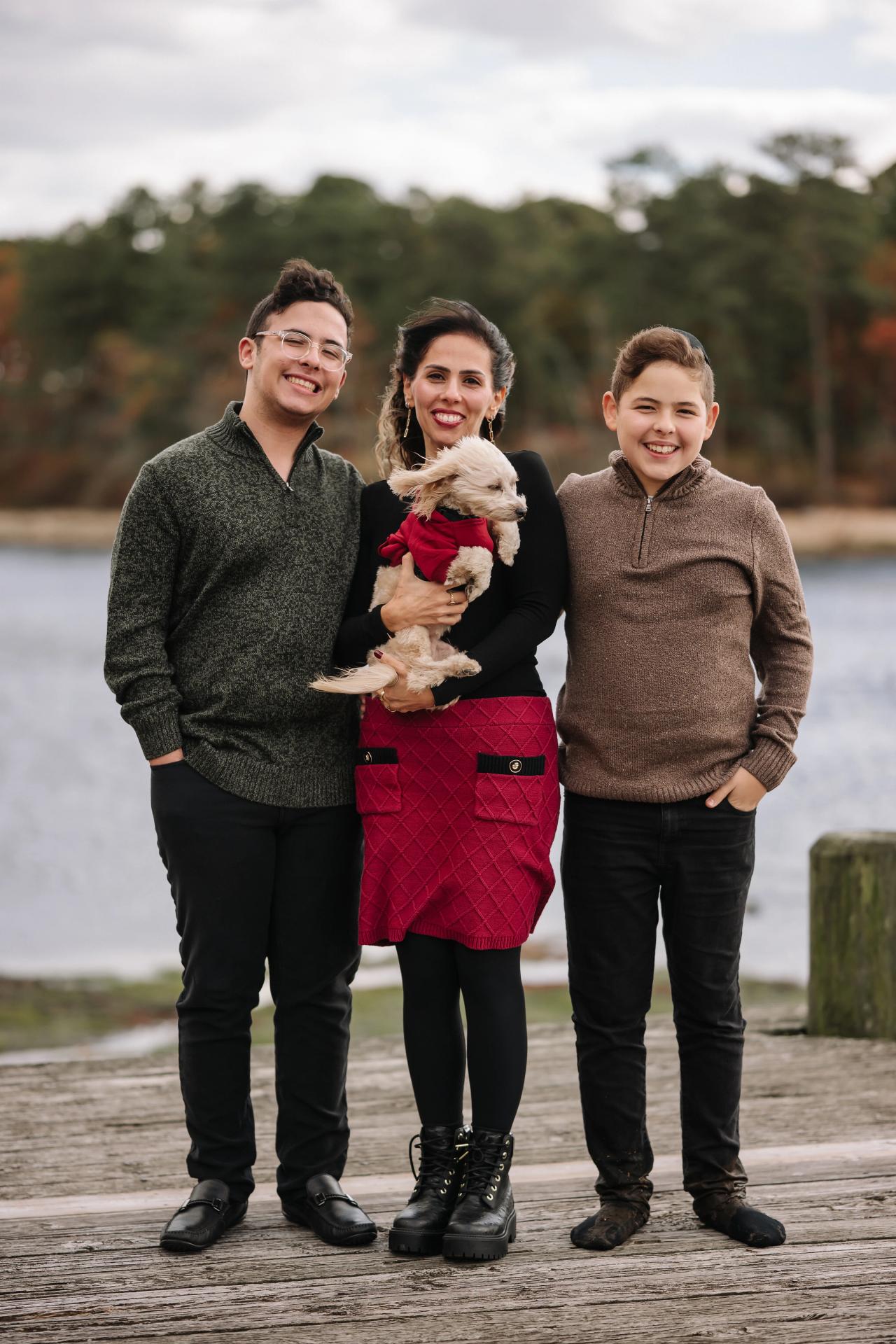 Full-length family portrait with a dog on a wooden lakeside dock