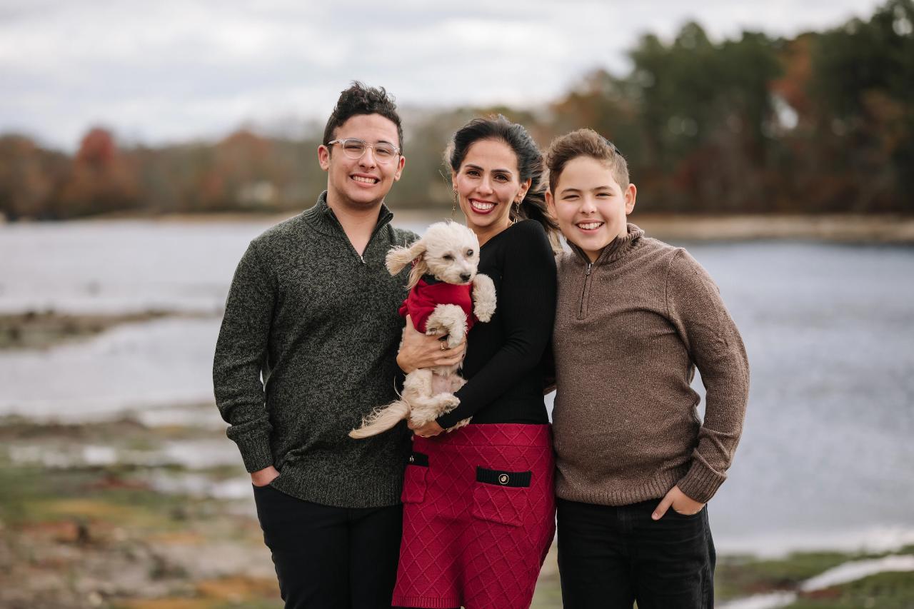 Family smiling together by the water with their dog