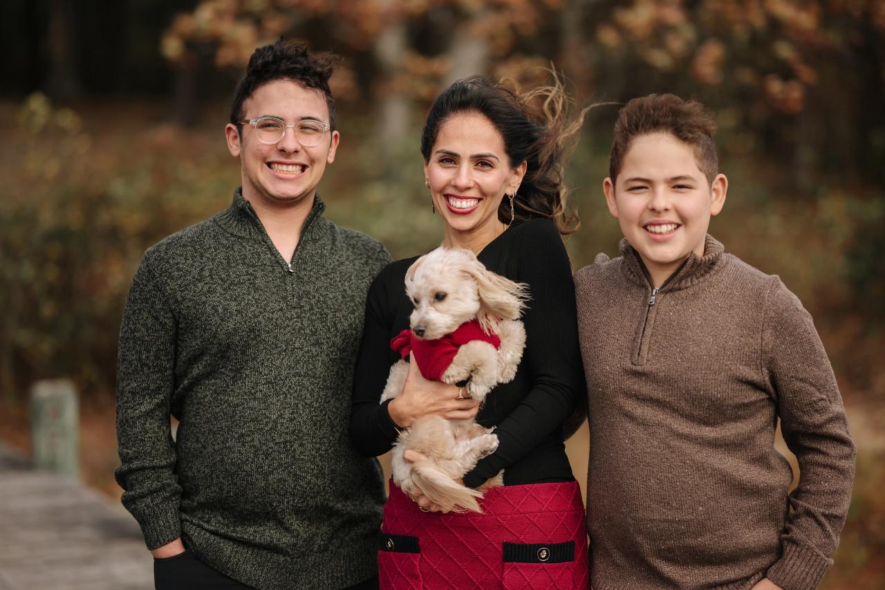 Close family portrait with a dog and autumn woodland behind them