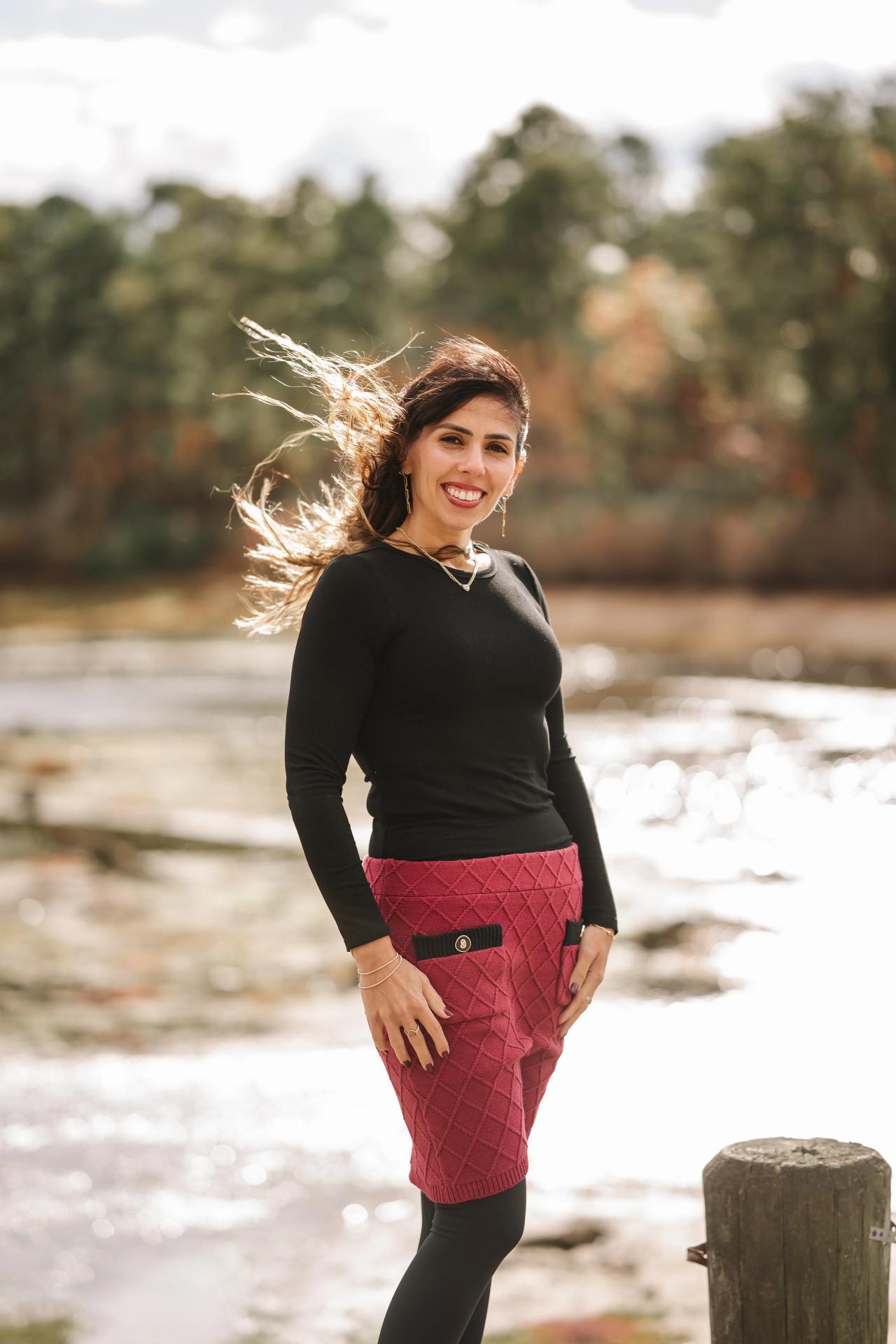 Outdoor portrait of a woman in a red skirt beside a lake