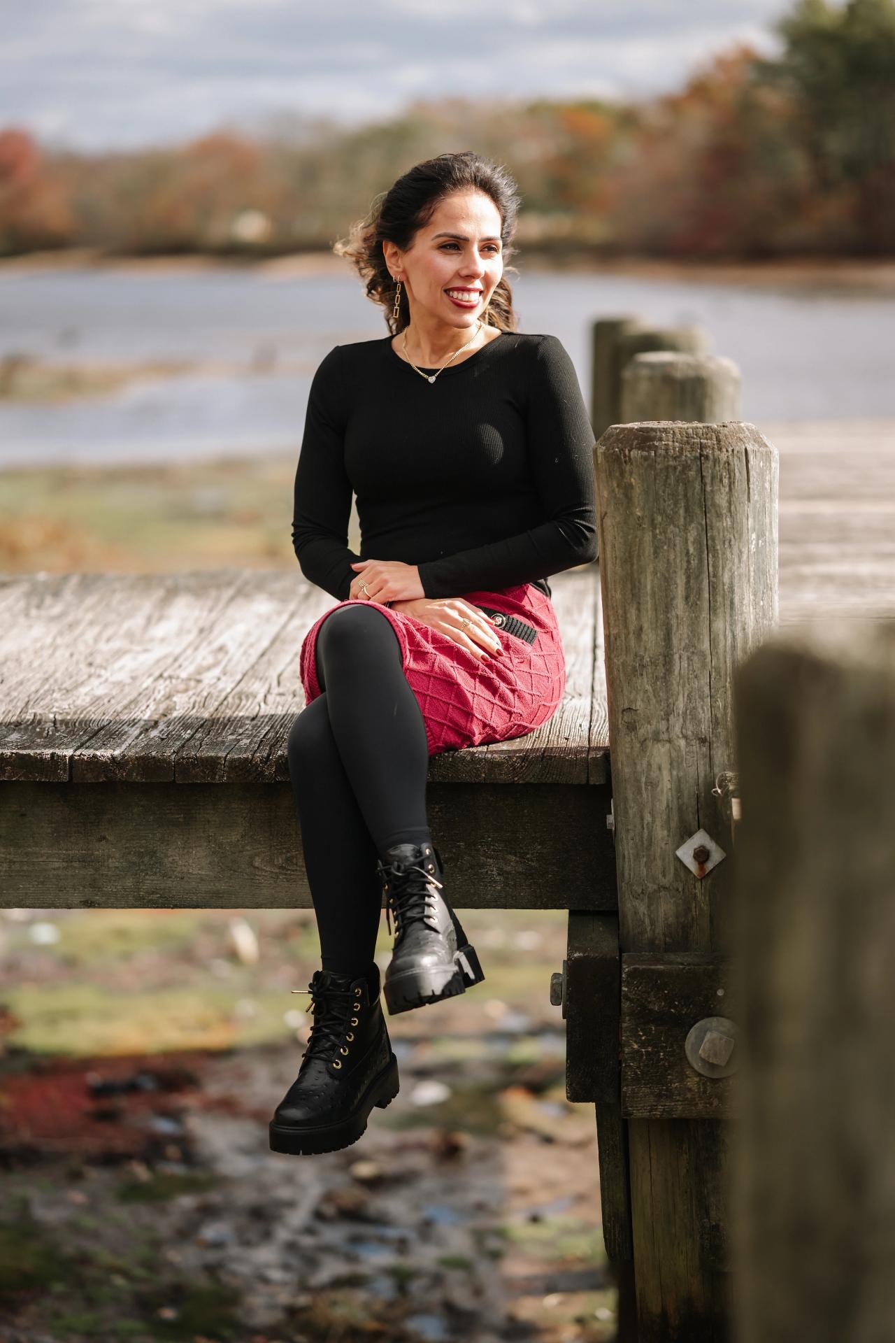 Relaxed portrait of a woman sitting beside a dock post
