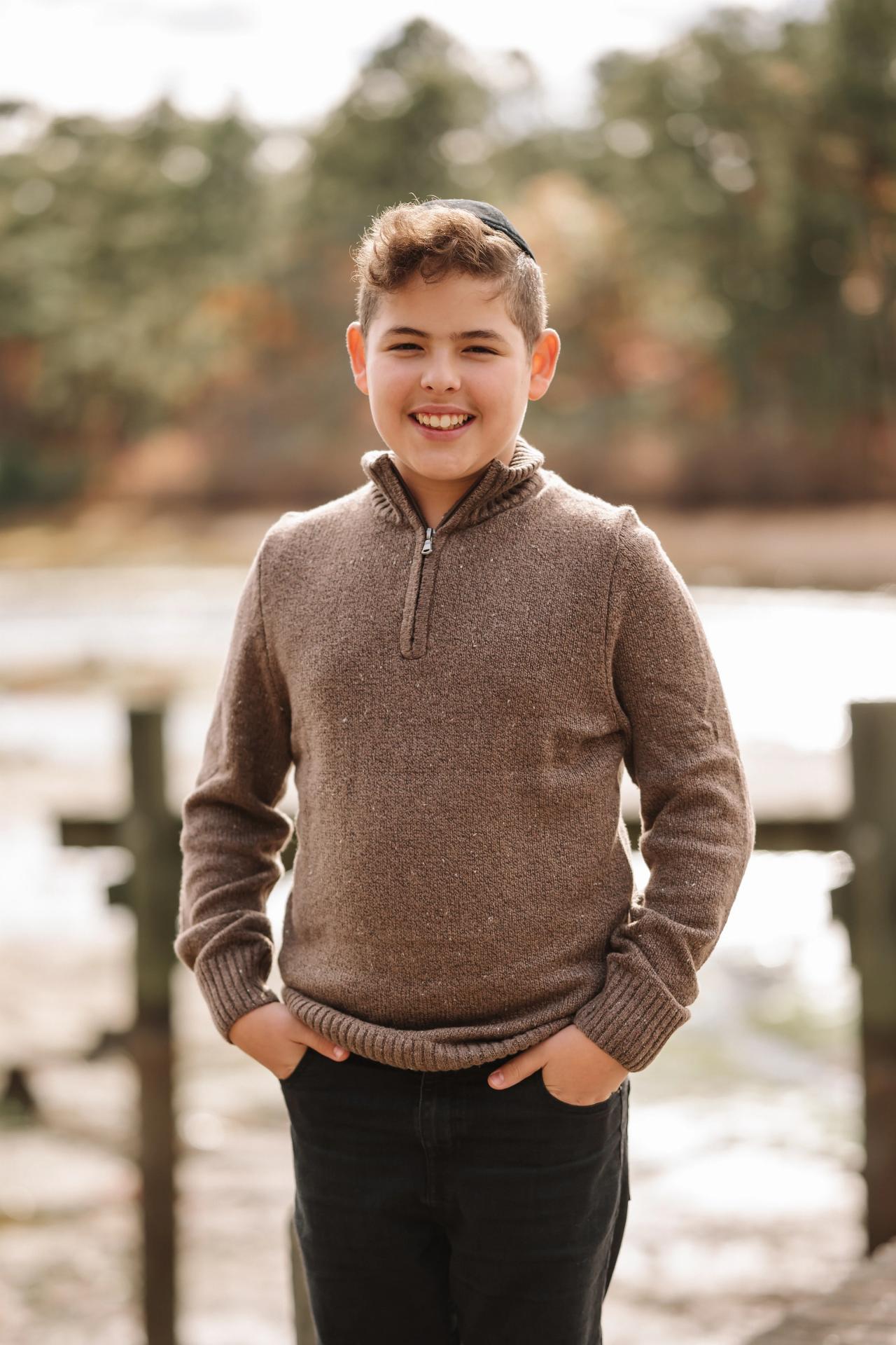Portrait of a boy in a brown sweater beside the lake