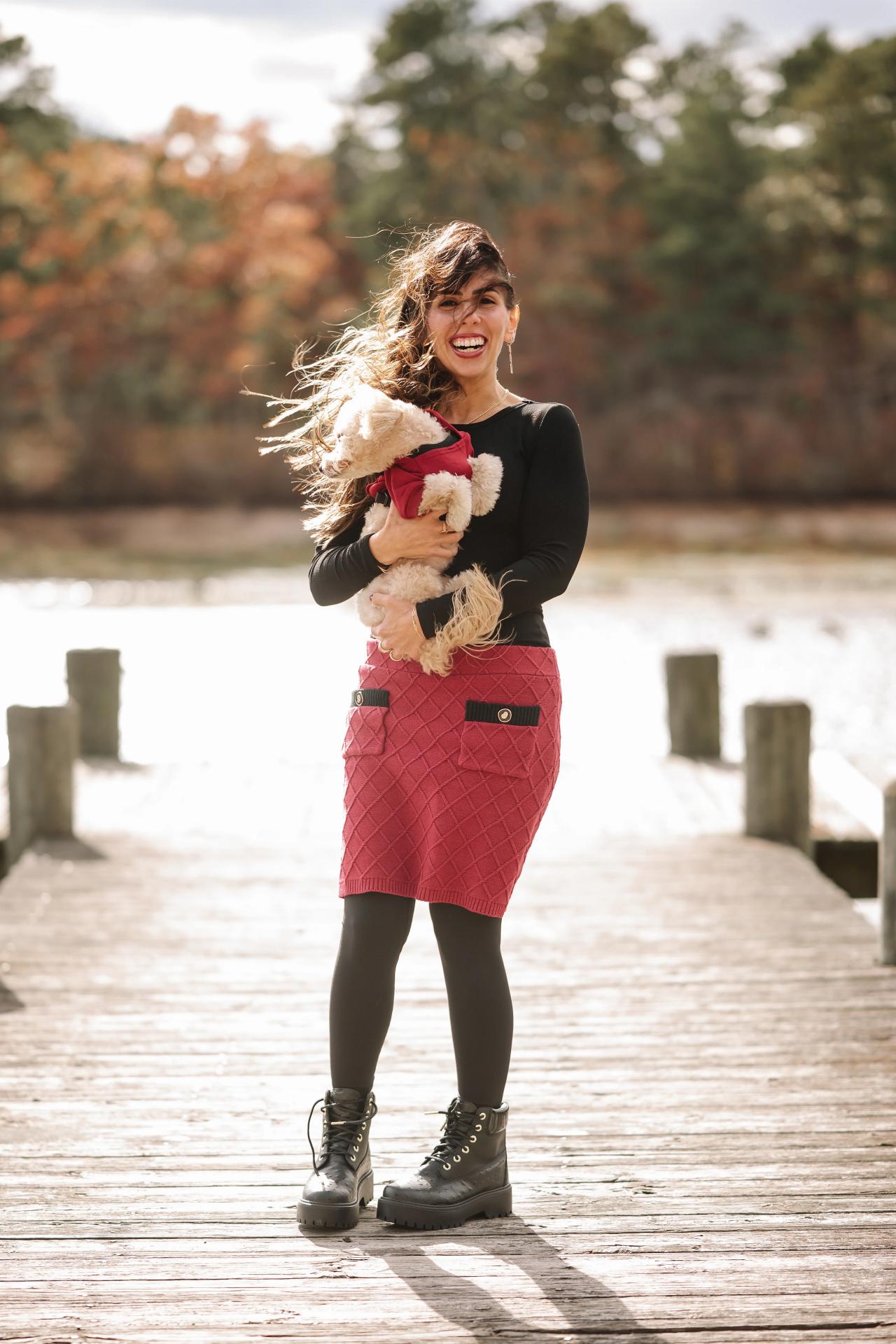 Woman holding her small dog on a wooden lakeside dock