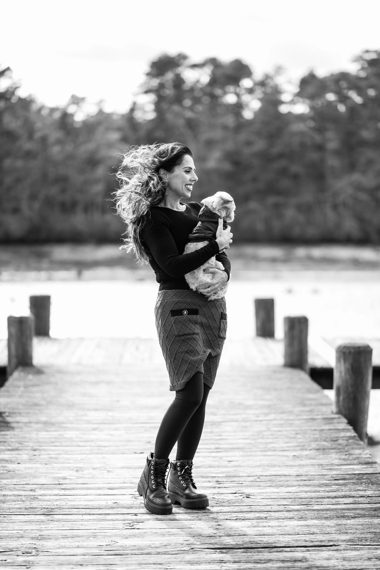 Black-and-white portrait of a woman holding her dog by the lake