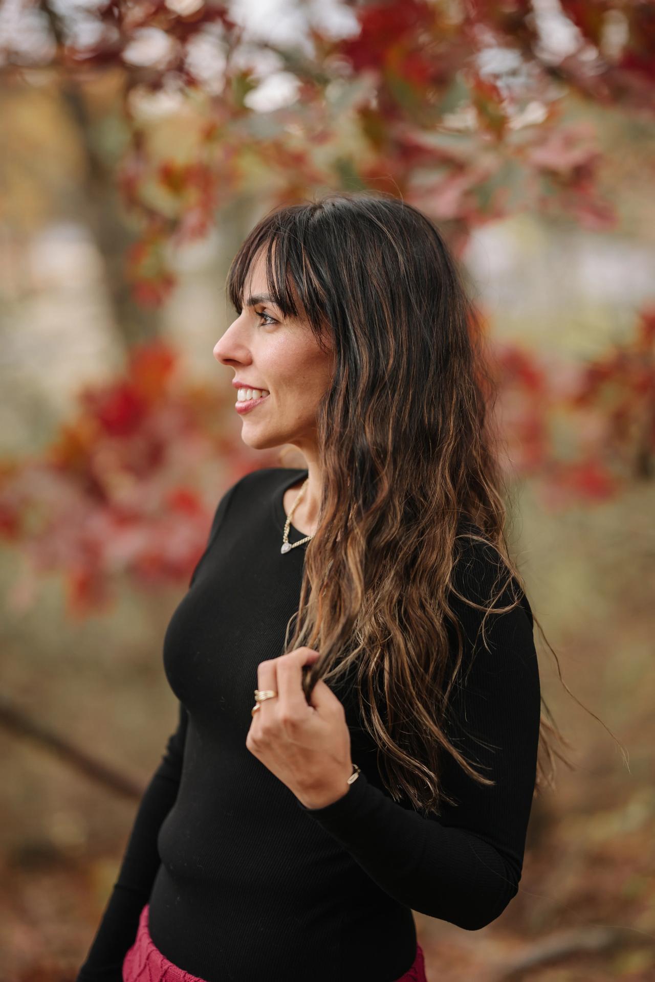 Side-profile portrait of a woman beneath autumn branches