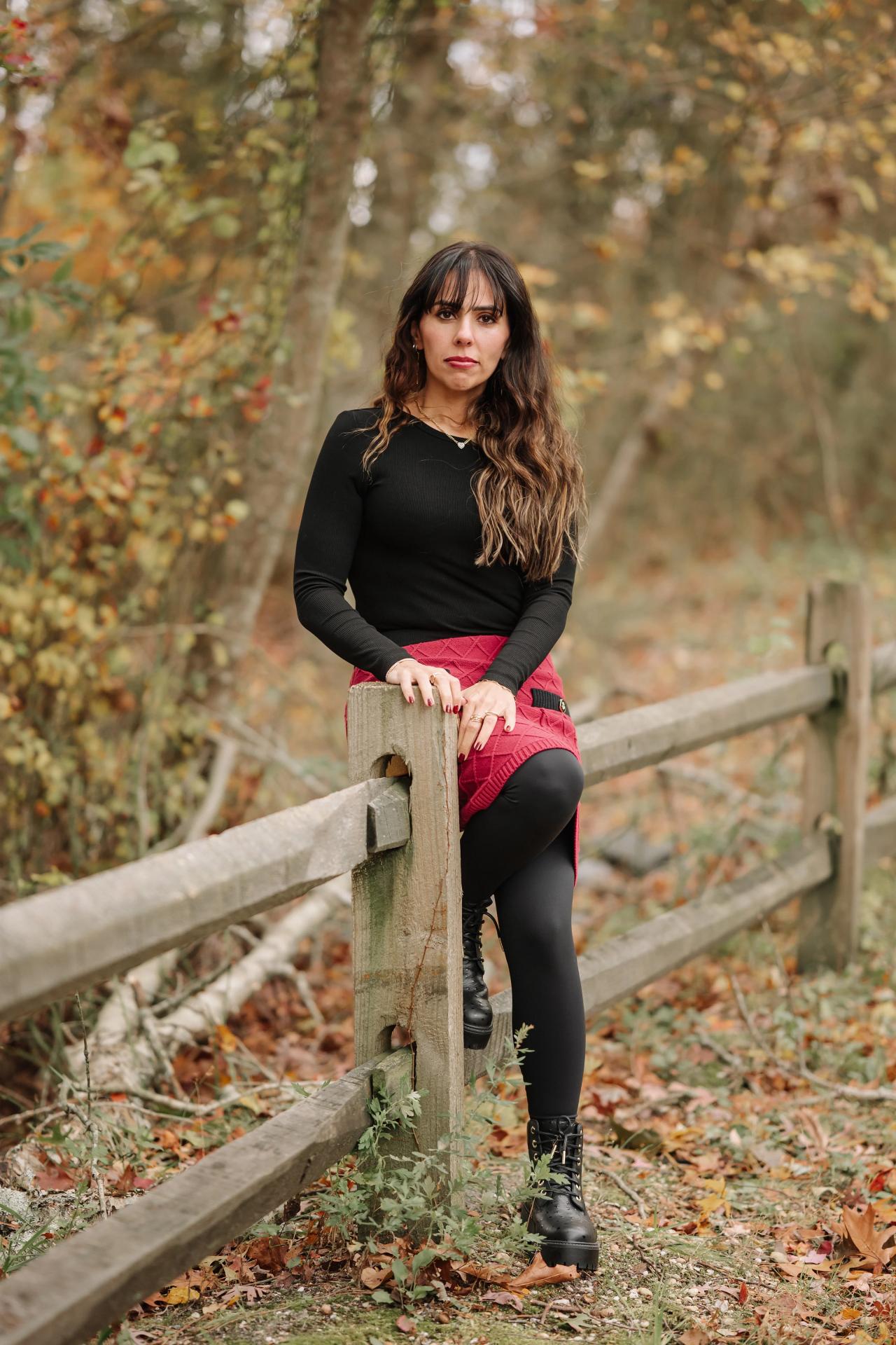 Woman seated on a wooden fence in autumn woodland