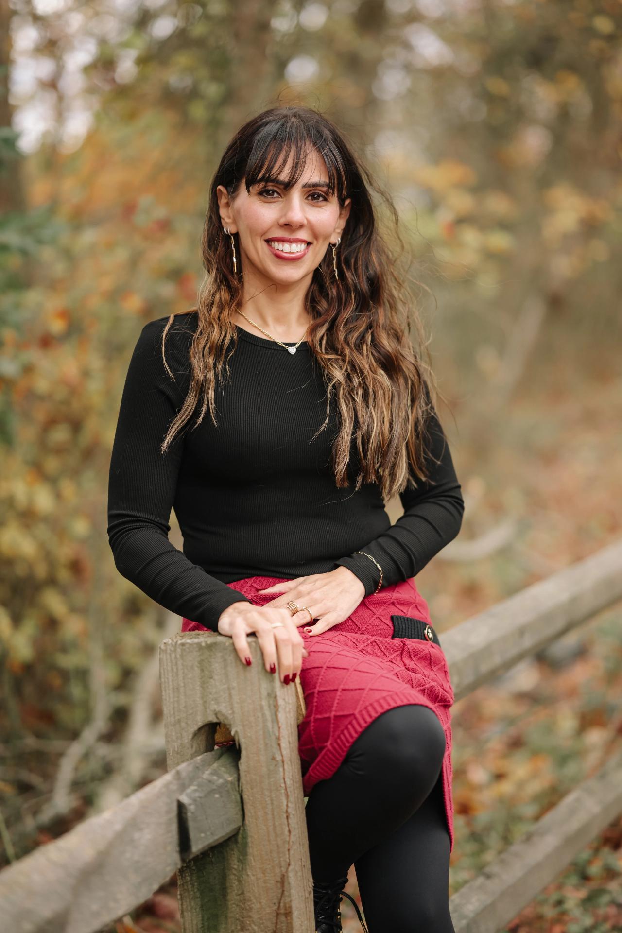 Close portrait of a woman smiling beside a woodland fence