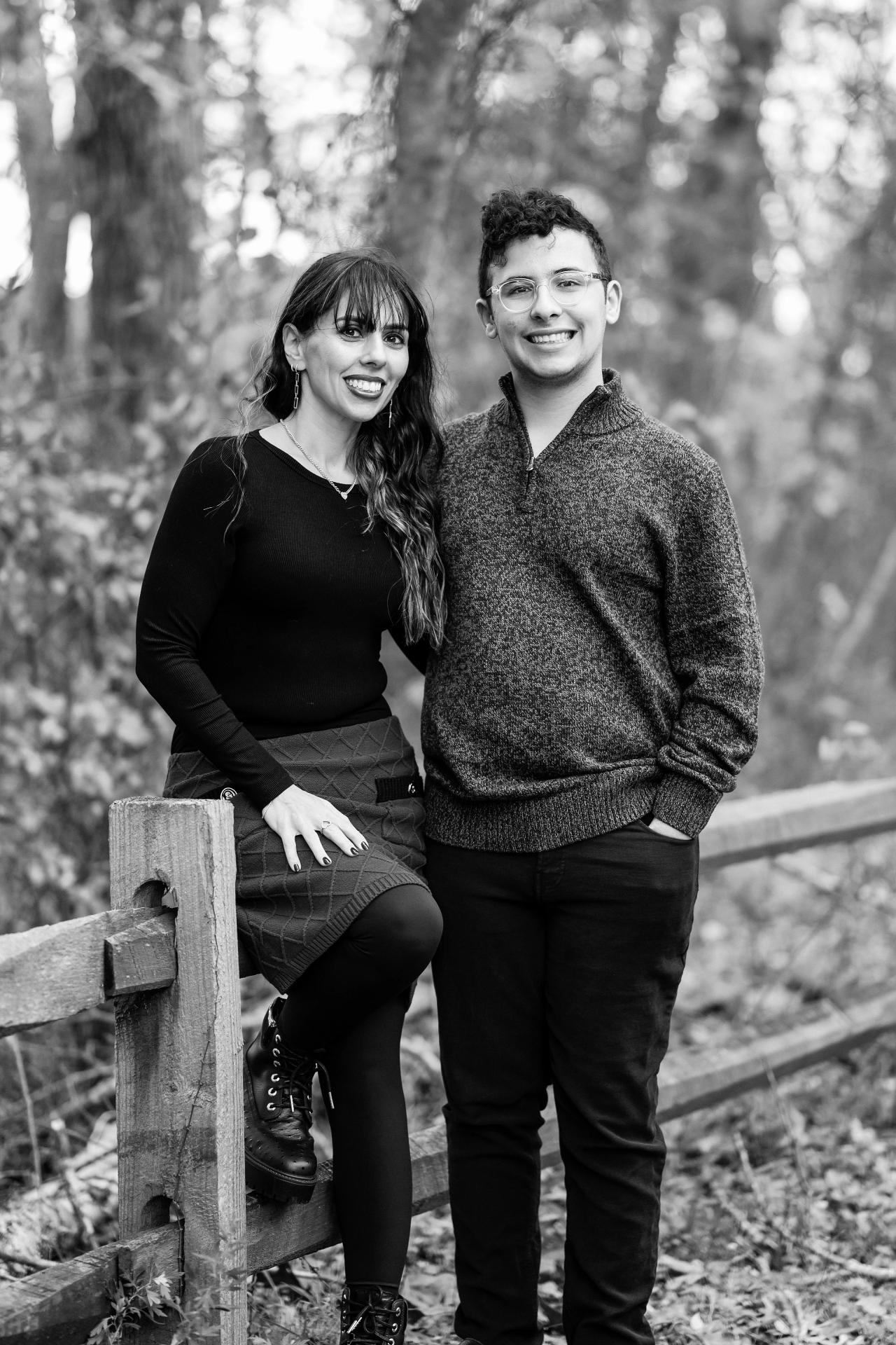 Black-and-white portrait of two family members beside a wooden fence