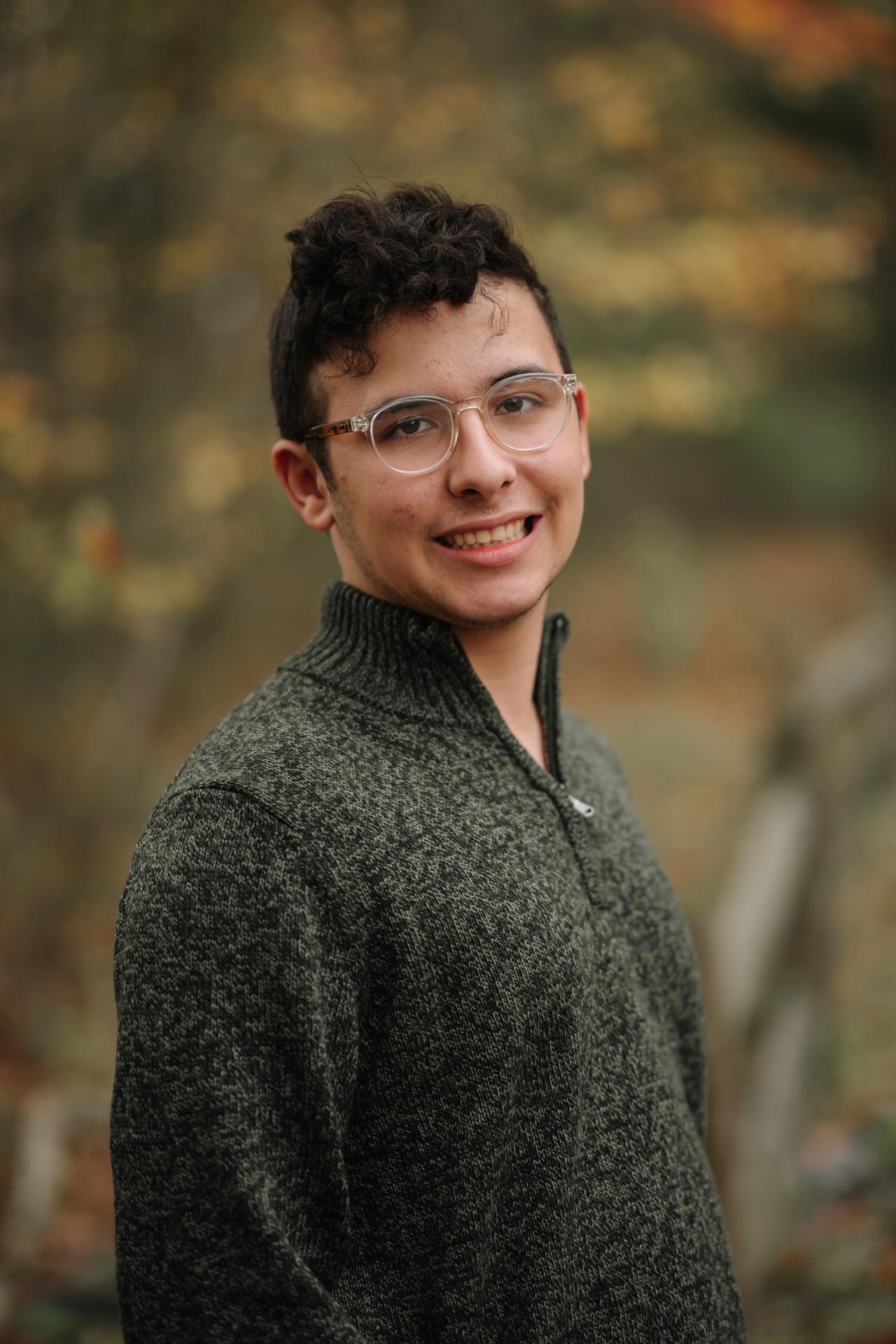 Close portrait of a young man with glasses against autumn woodland