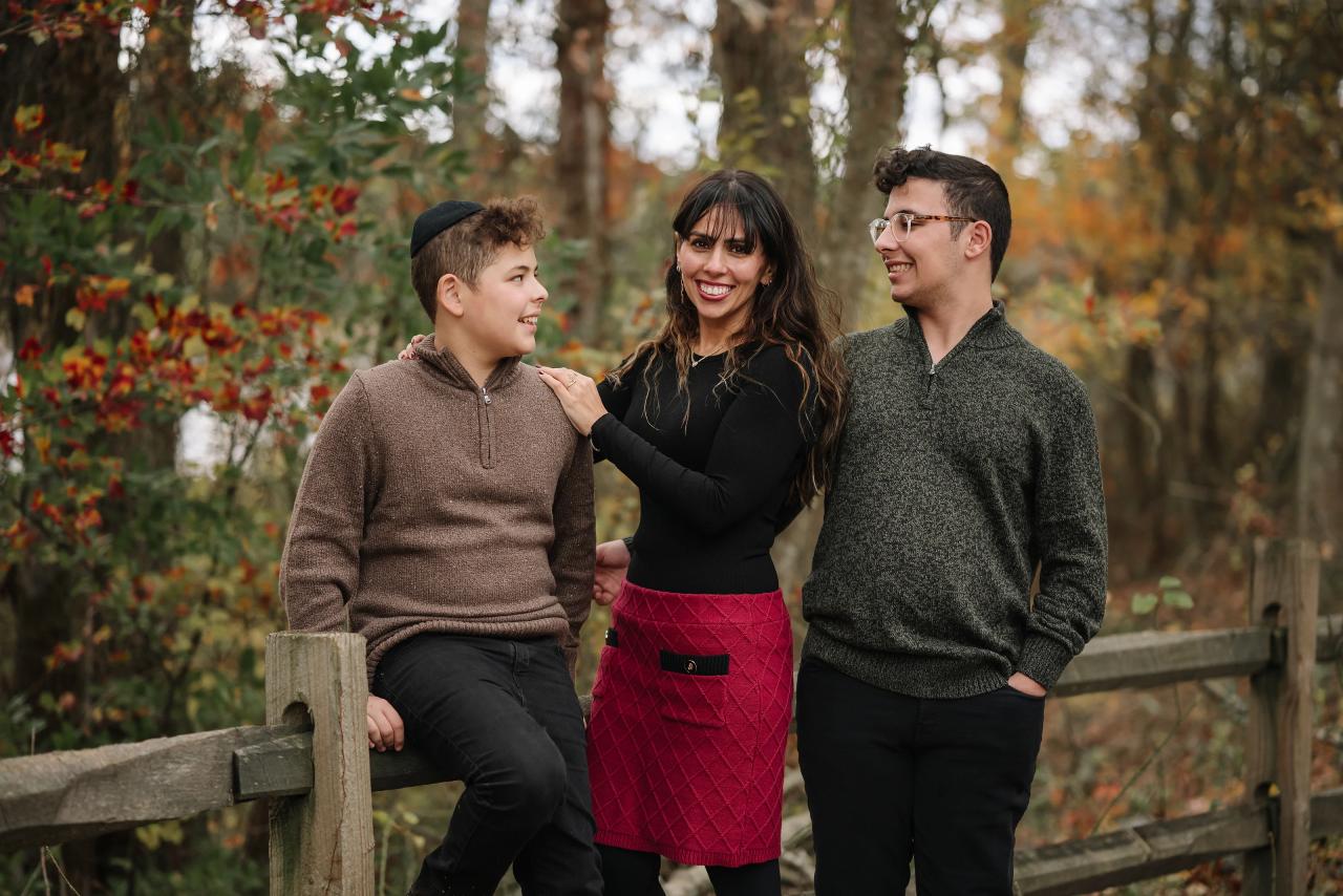 Family sharing a candid moment beside a woodland fence