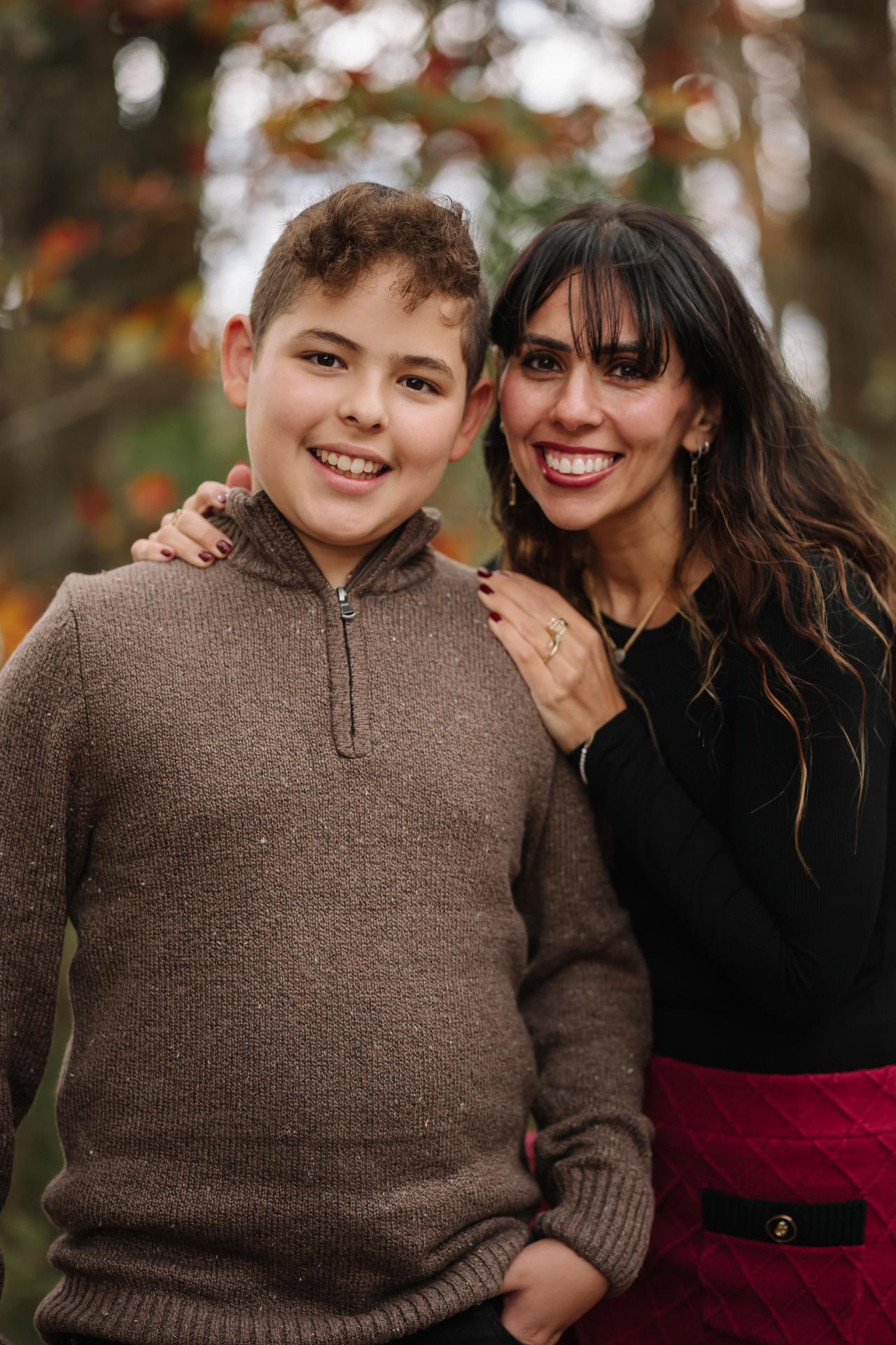 Close portrait of a woman and boy smiling together among autumn trees