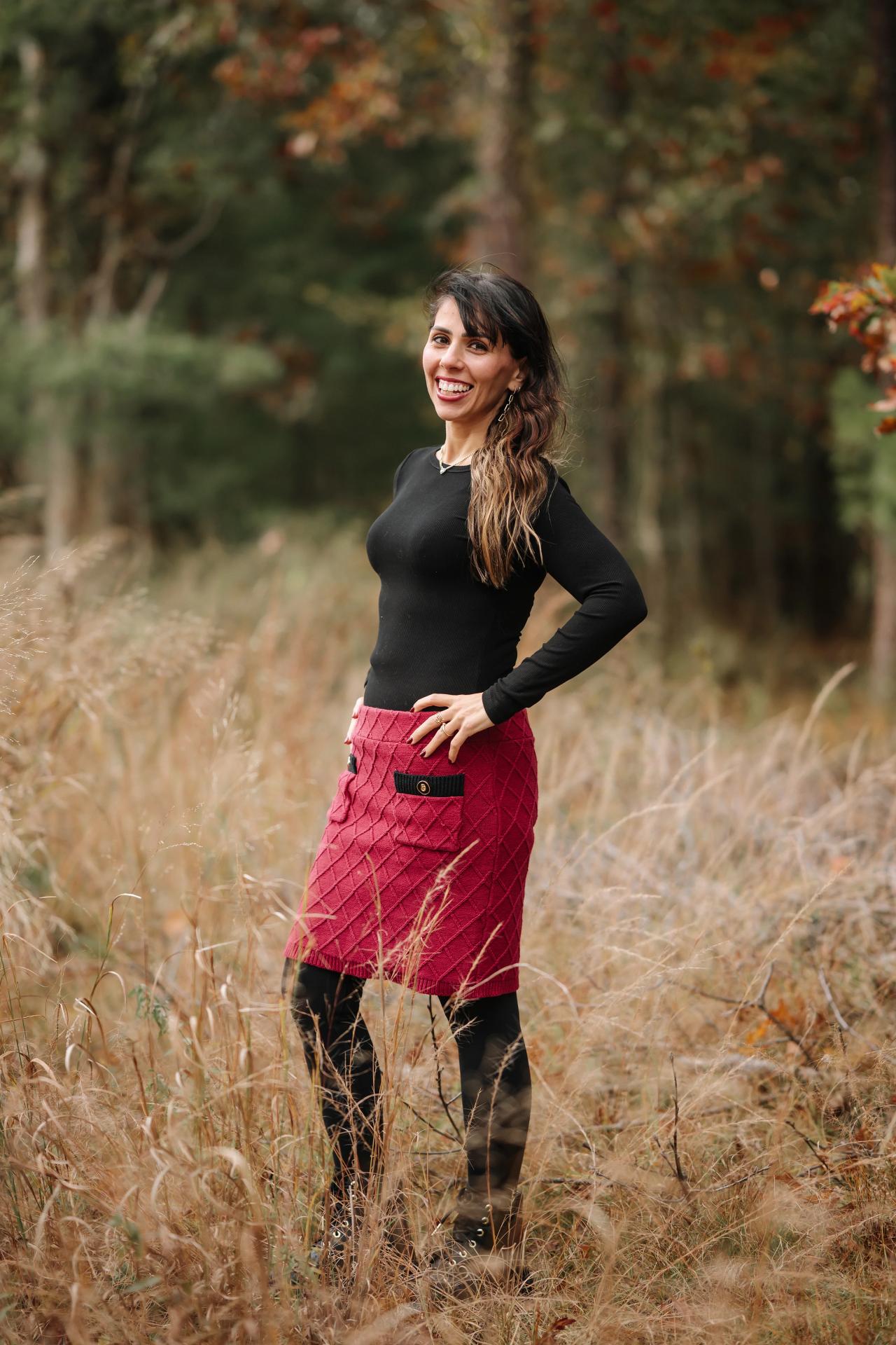 Woman in a red skirt standing in tall grasses during an outdoor portrait session